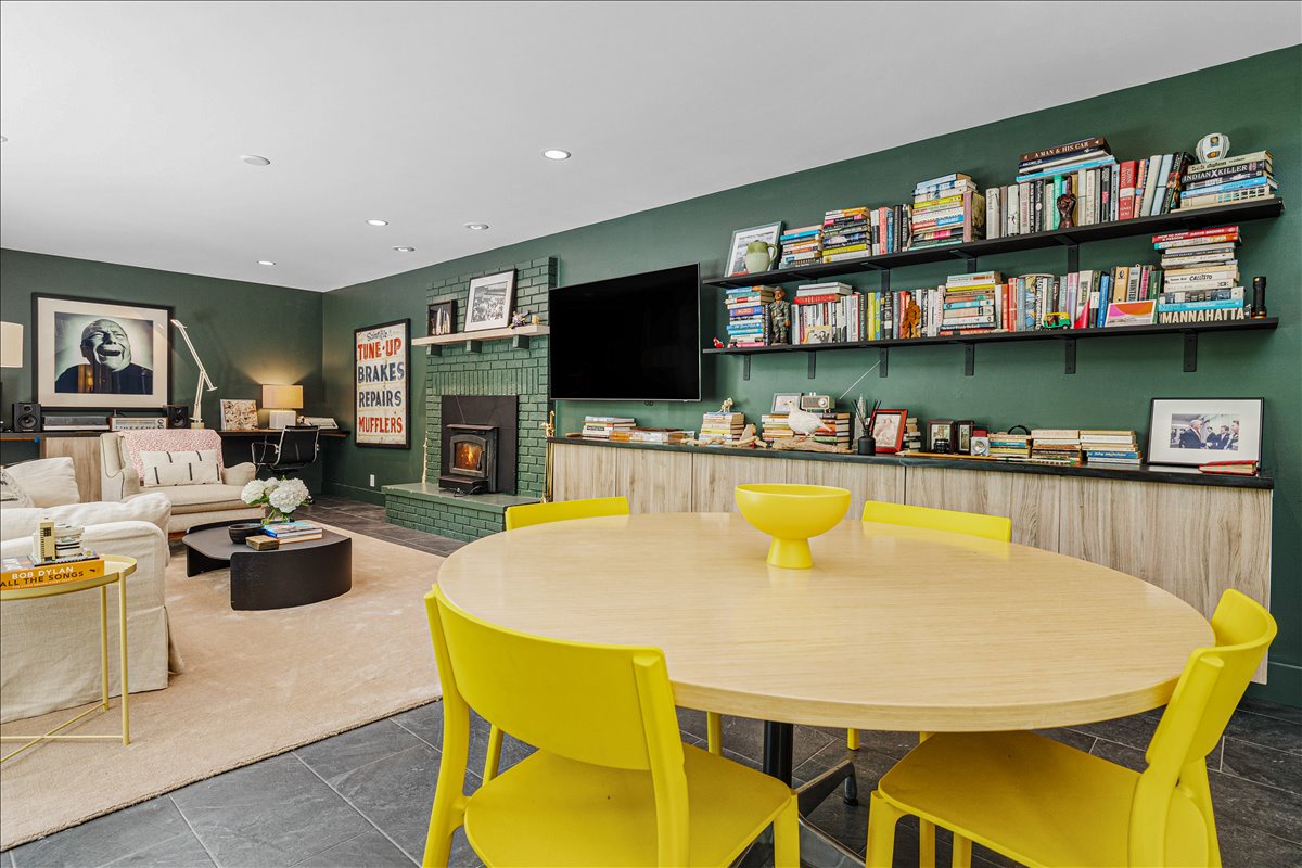 Unwind in your stylish living space with vibrant yellow chairs, cozy fireplace, and extensive book collection for quiet evenings.