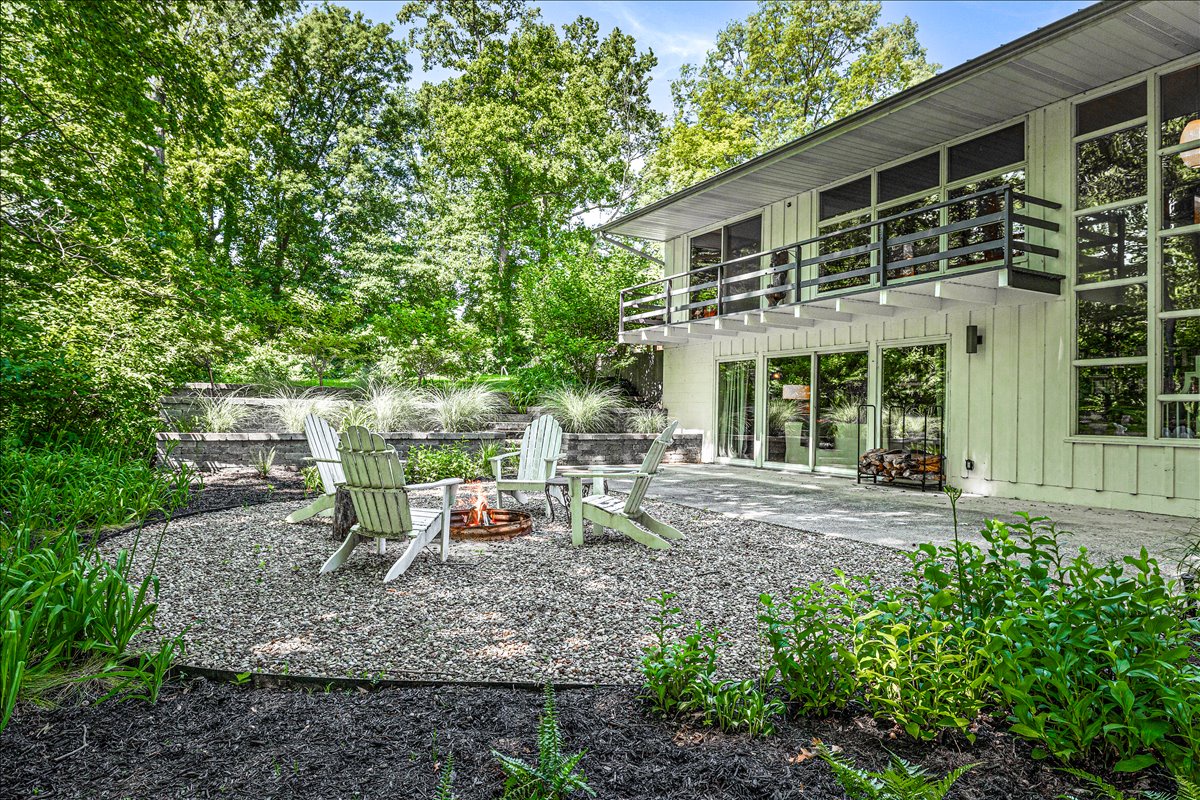 Modern retreat nestled among mature trees with outdoor seating area and contemporary architecture.
