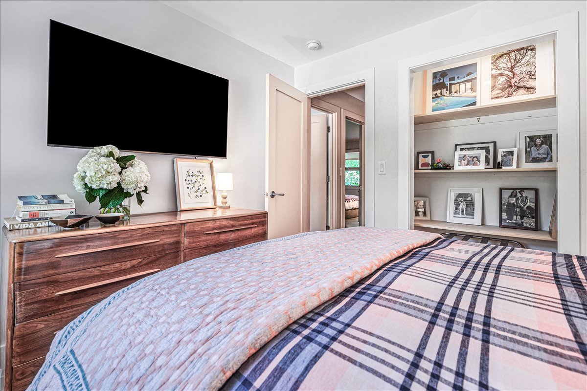 Sink into your comfortable bed while enjoying shows on the wall-mounted TV in this thoughtfully designed bedroom with beautiful built-in shelving.