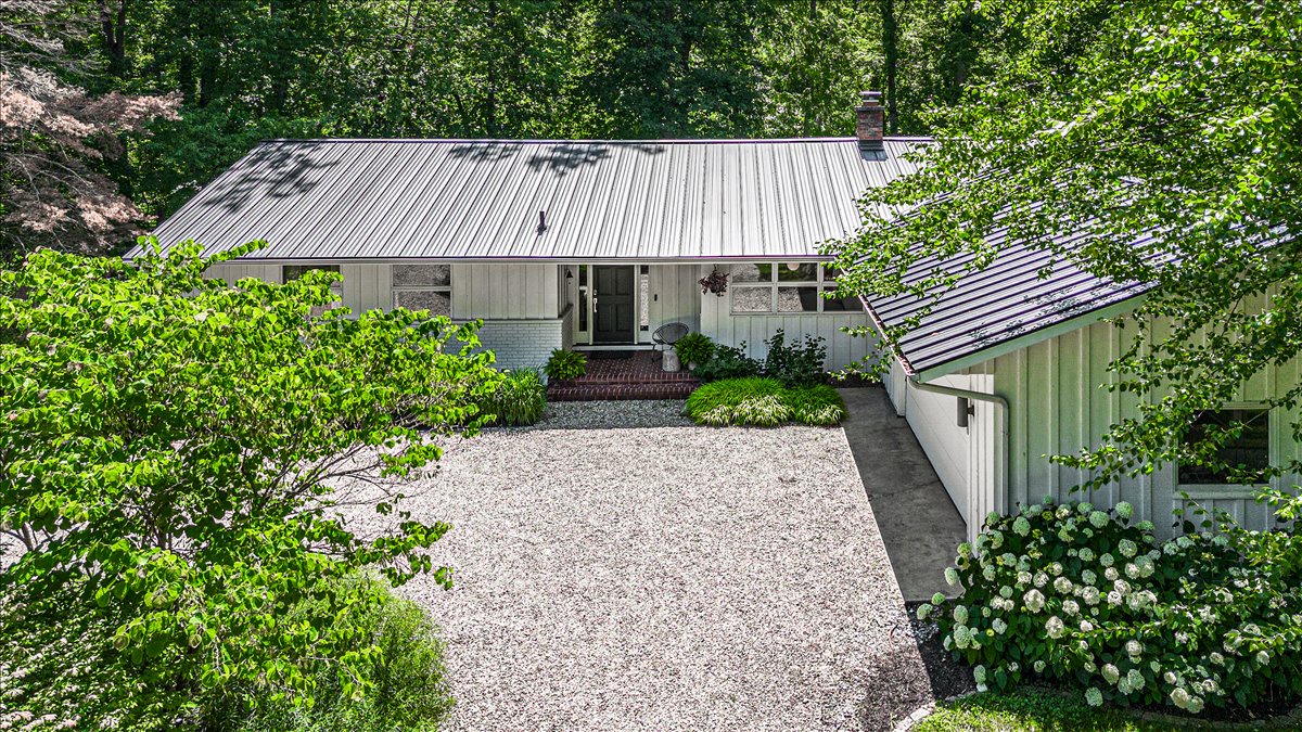 Modern retreat nestled in lush forest with private gravel courtyard and charming landscaped gardens.