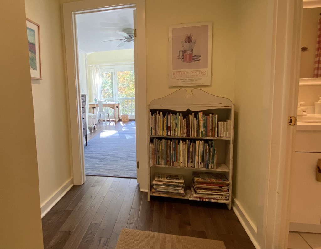 Bookshelf upstairs stocked with old children's books, with primary bedroom beyond.