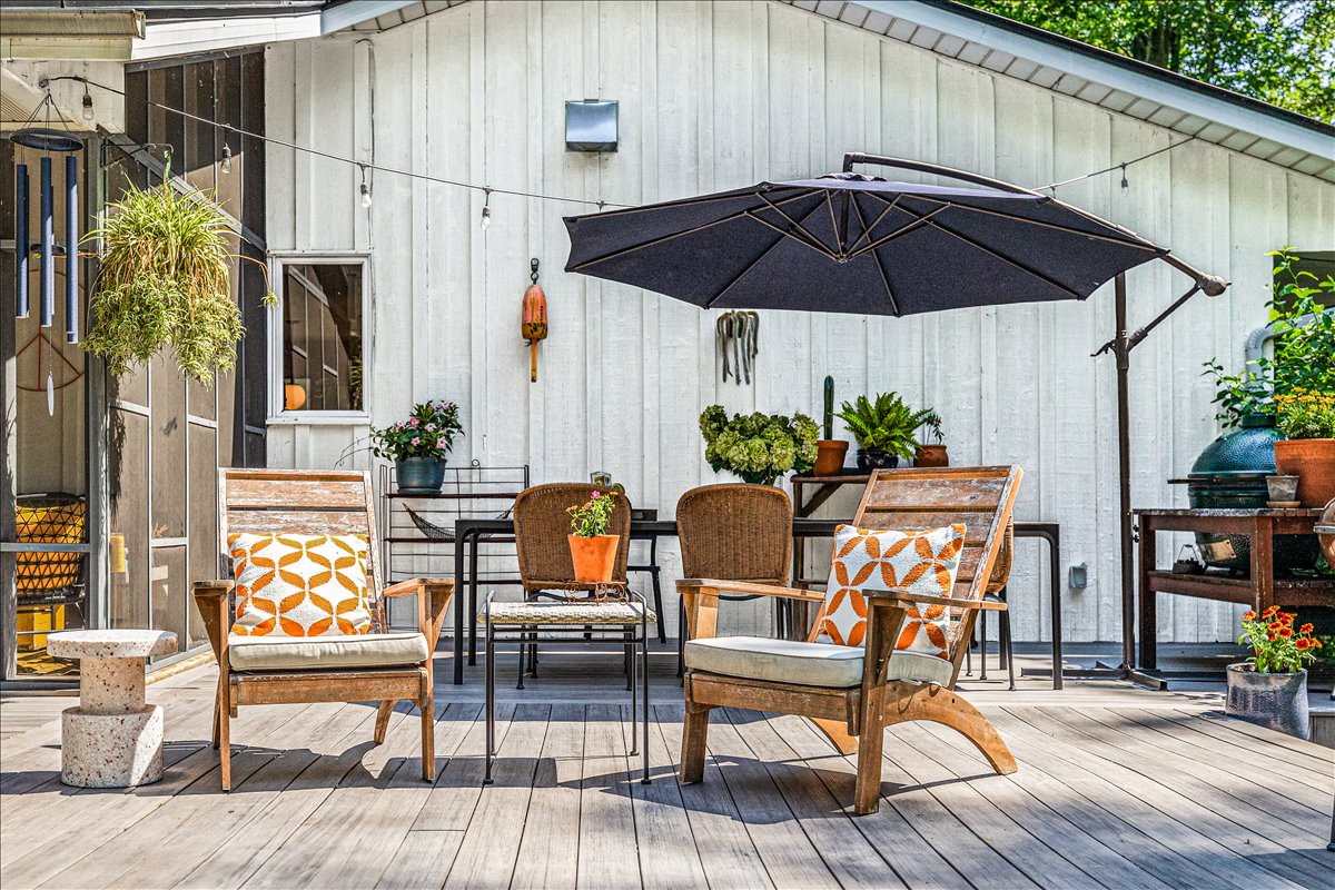 Your private patio invites relaxation with stylish seating, vibrant orange accents, and a large umbrella for perfect shade during sunny afternoons.