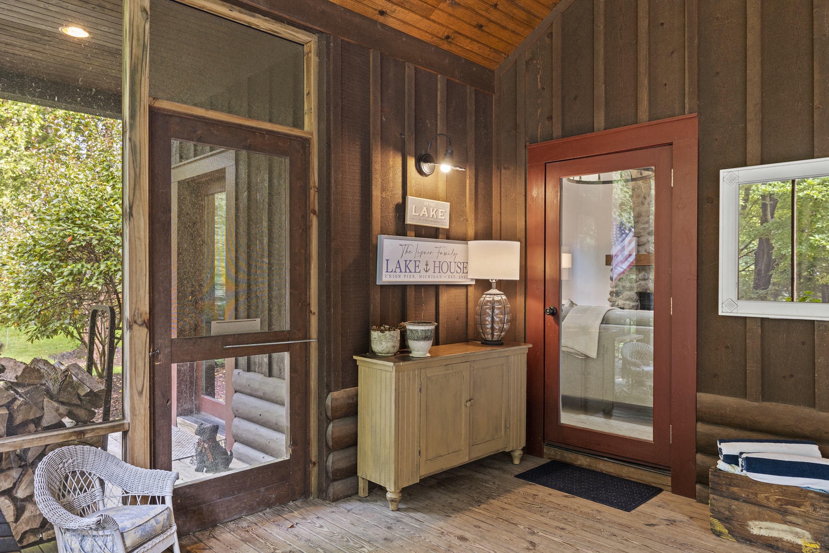 This inviting covered porch greets you with warm wood-paneled walls, thoughtful décor, and a cozy nook to store firewood before stepping inside.