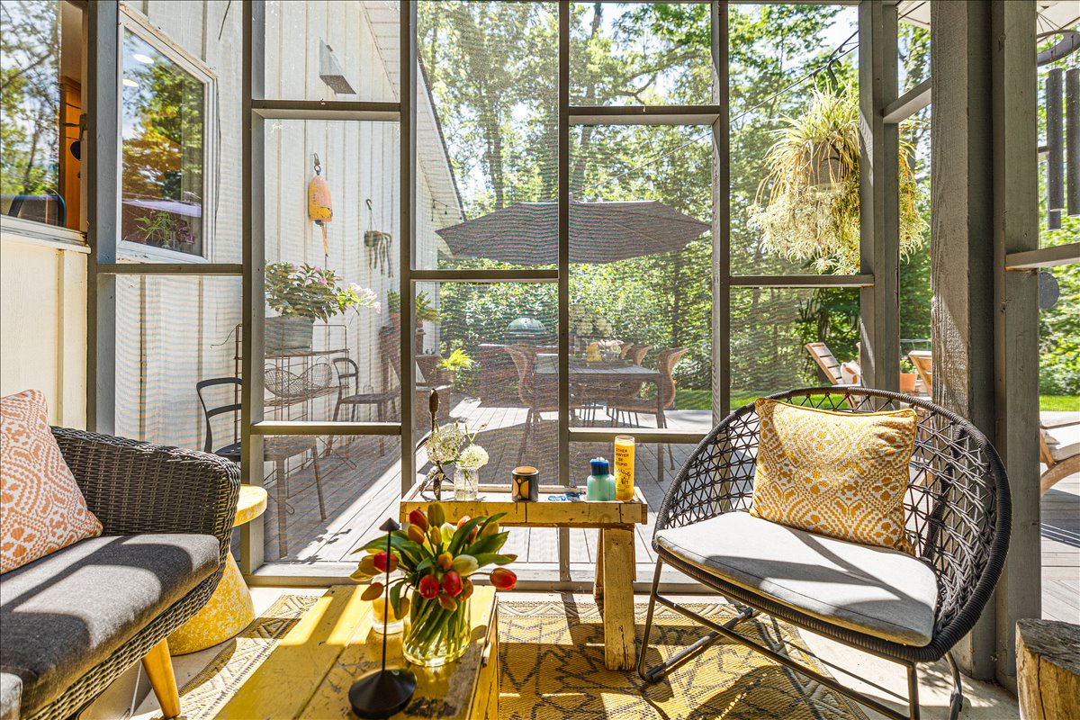 Relax in your bright sunroom where floor-to-ceiling windows frame garden views and stylish seating invites peaceful moments with morning coffee.