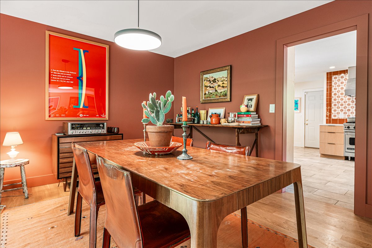 Gather around this stunning mid-century dining table where warm terracotta walls and curated art create your perfect dinner party backdrop.
