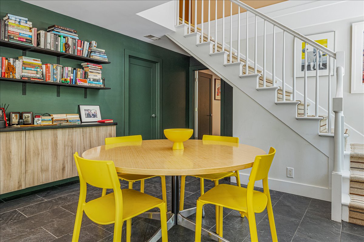 Gather around this vibrant yellow dining set where your morning coffee and evening meals become memorable moments in this bright, book-filled space.