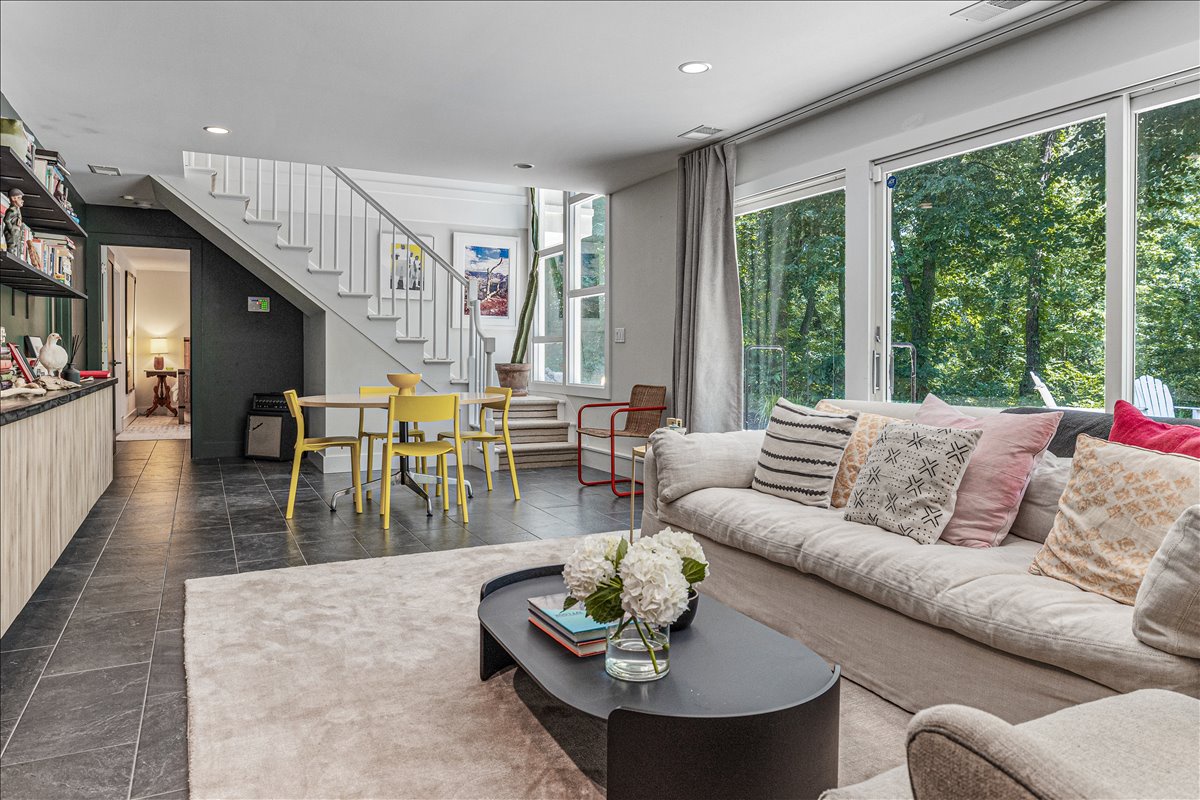 Settle into your bright, stylish living space where forest views frame cozy seating and colorful accents invite relaxation.