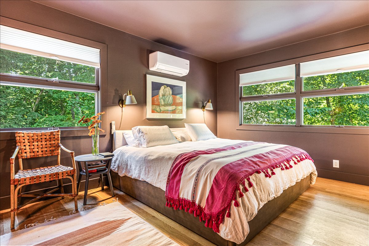 Rest peacefully in your stylish bedroom surrounded by lush treetop views and warm natural light streaming through large windows.