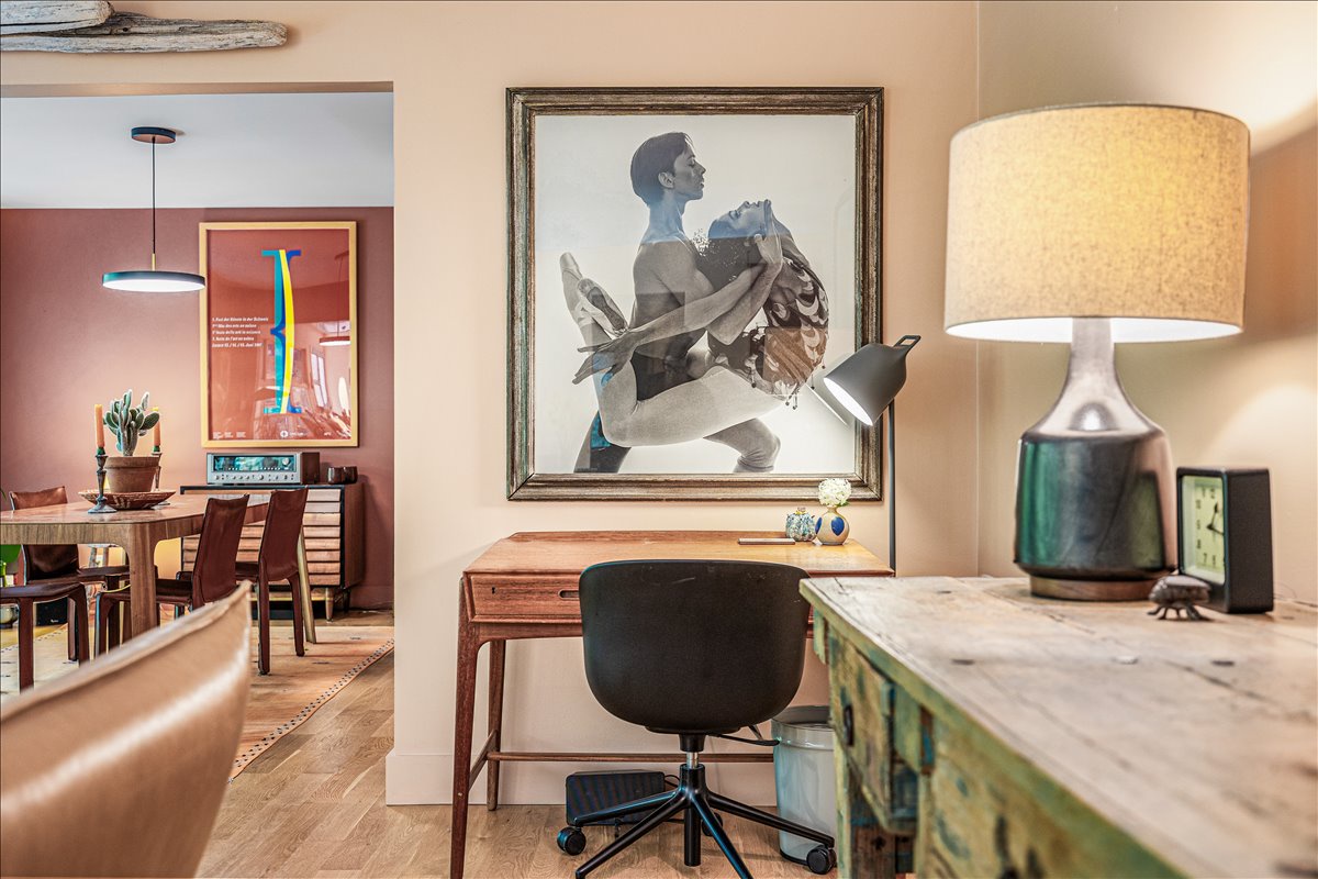 Work comfortably at your stylish desk with artistic surroundings and warm lighting creating the perfect productive atmosphere.