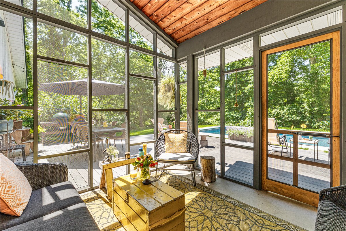 Relax in this sun-drenched enclosed porch with pool views, where morning coffee tastes better surrounded by nature's beauty.
