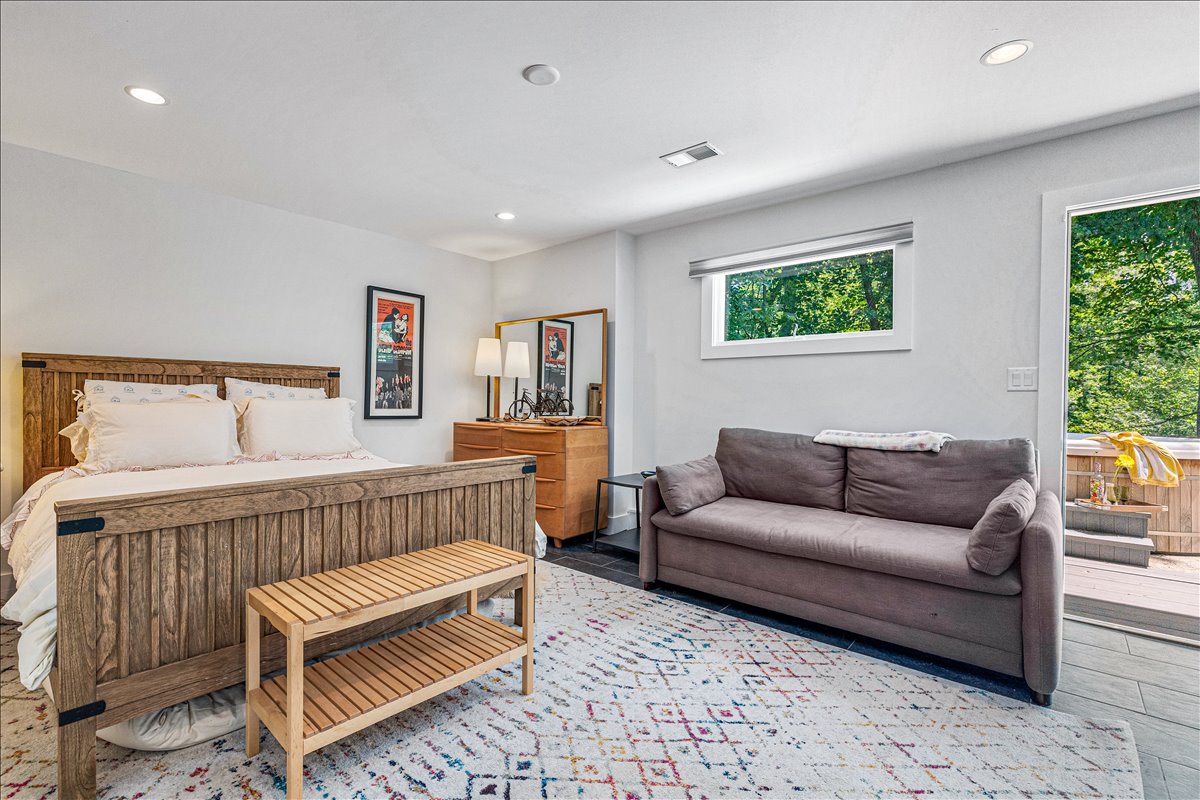 Your spacious suite blends comfort and style with a plush bed, cozy sofa, and forest views through bright windows.