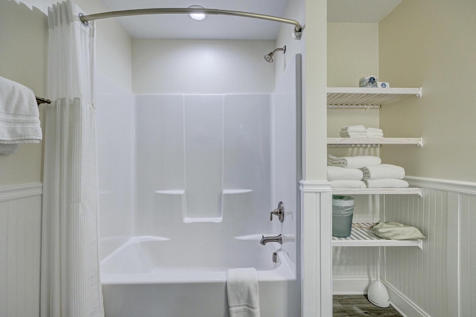 Unwind in your spacious bathroom featuring a deep soaking tub and organized shelving stocked with fresh towels for your comfort.