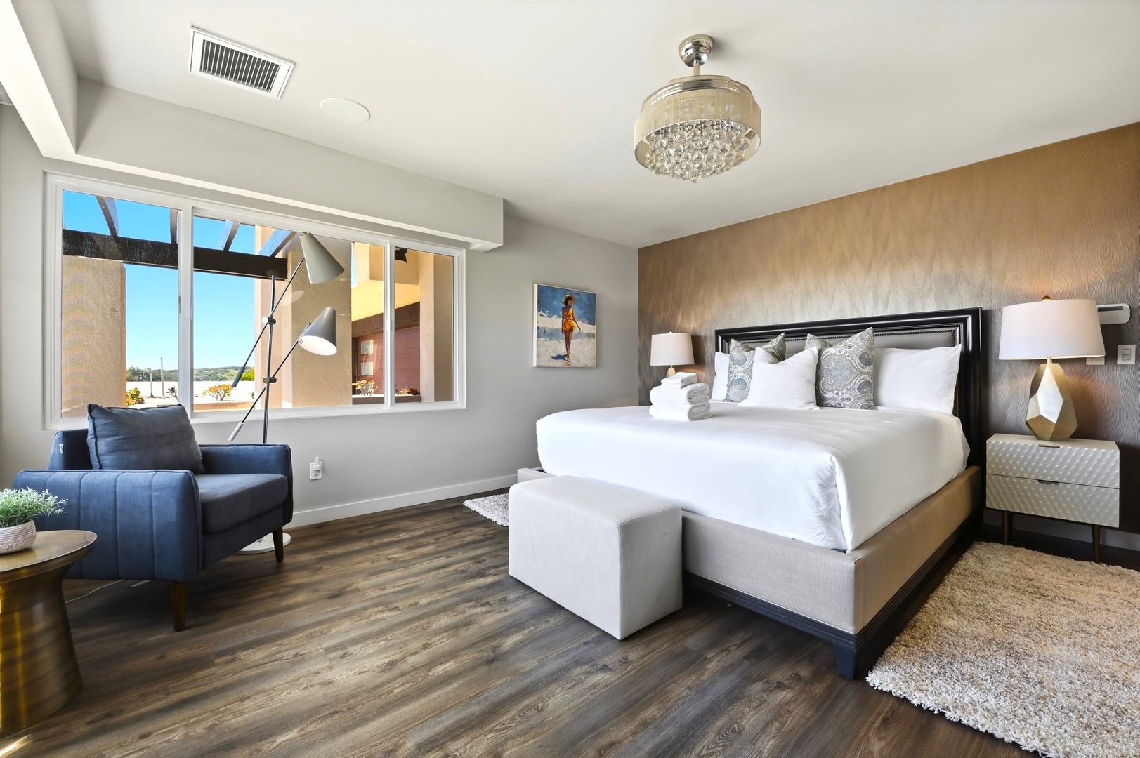 Sink into luxurious comfort in your stylish master suite, featuring plush bedding and a cozy reading chair by windows.