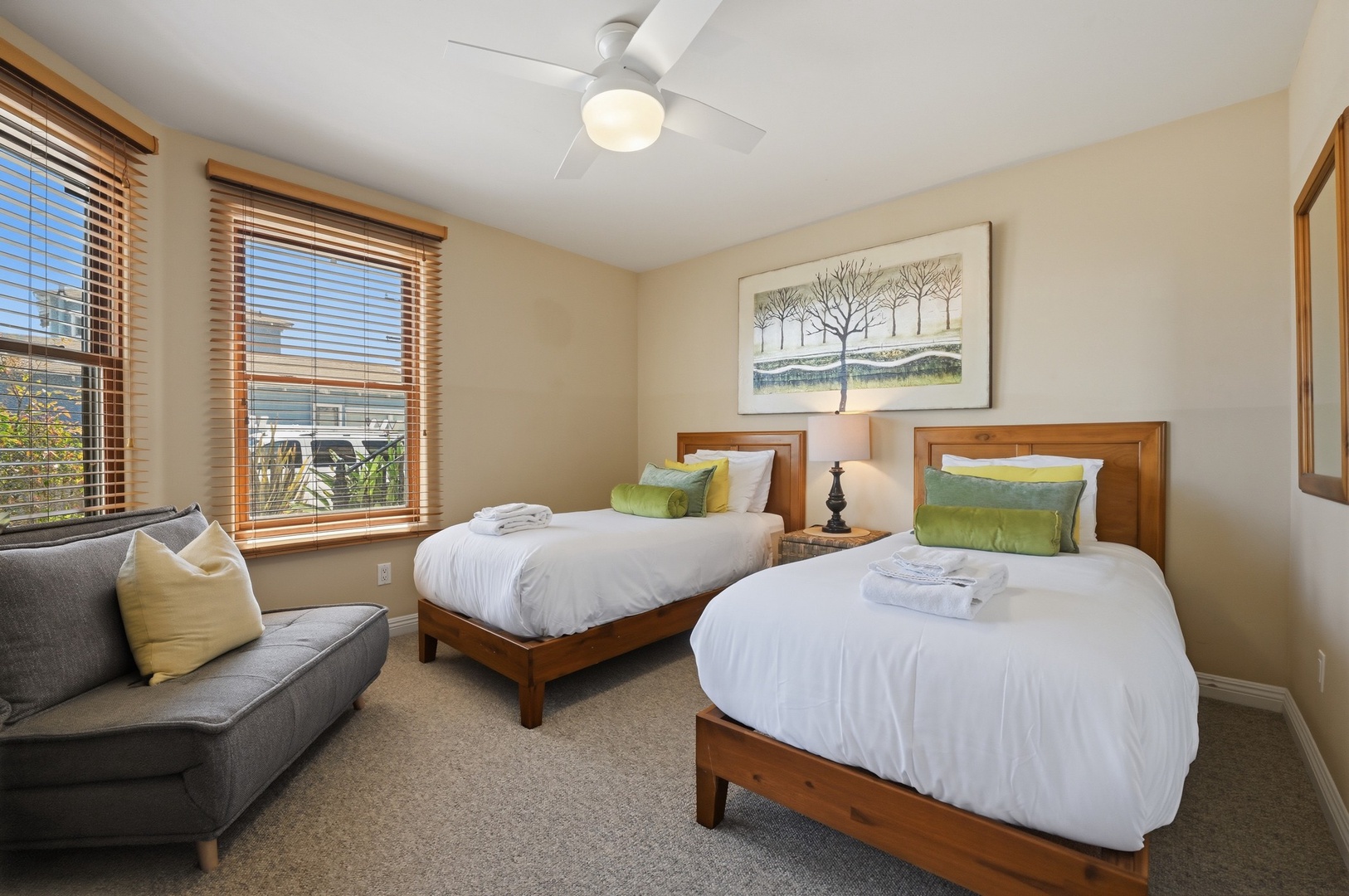 Relax in your spacious twin bedroom with crisp linens, modern furnishings, and natural light streaming through wooden blinds.