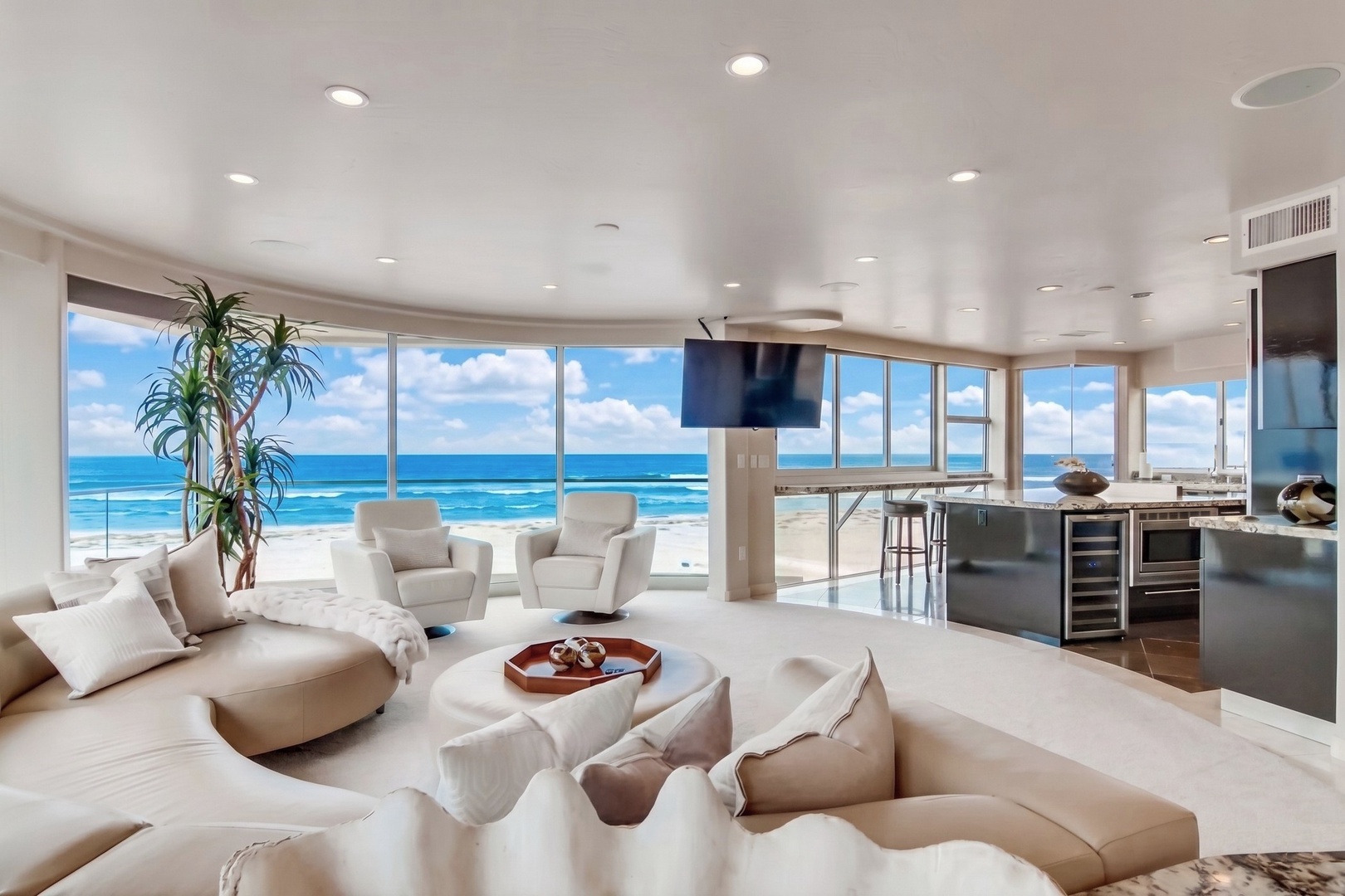 Stunning beachfront living space where floor-to-ceiling windows frame endless ocean views, while a sleek open kitchen invites culinary adventures. Sink into plush seating and feel the luxury of coastal living.