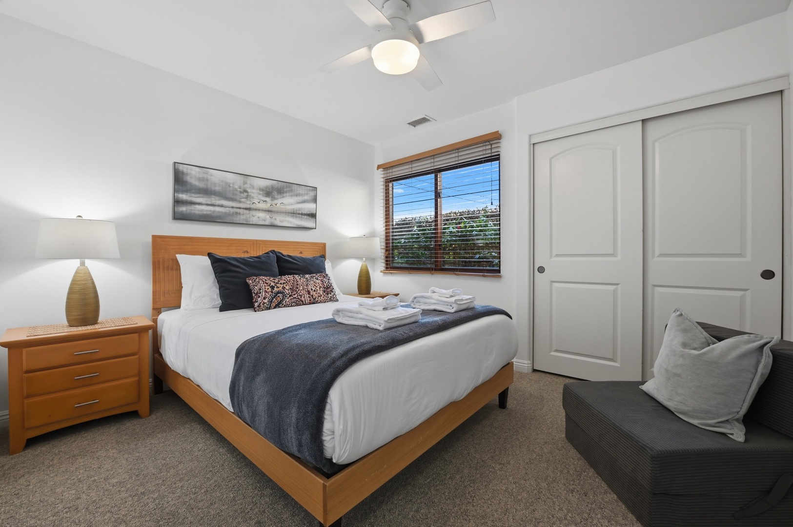 Sink into your cozy bedroom retreat with crisp linens, warm wood furnishings, and a gentle ceiling fan creating the perfect atmosphere for restful nights.