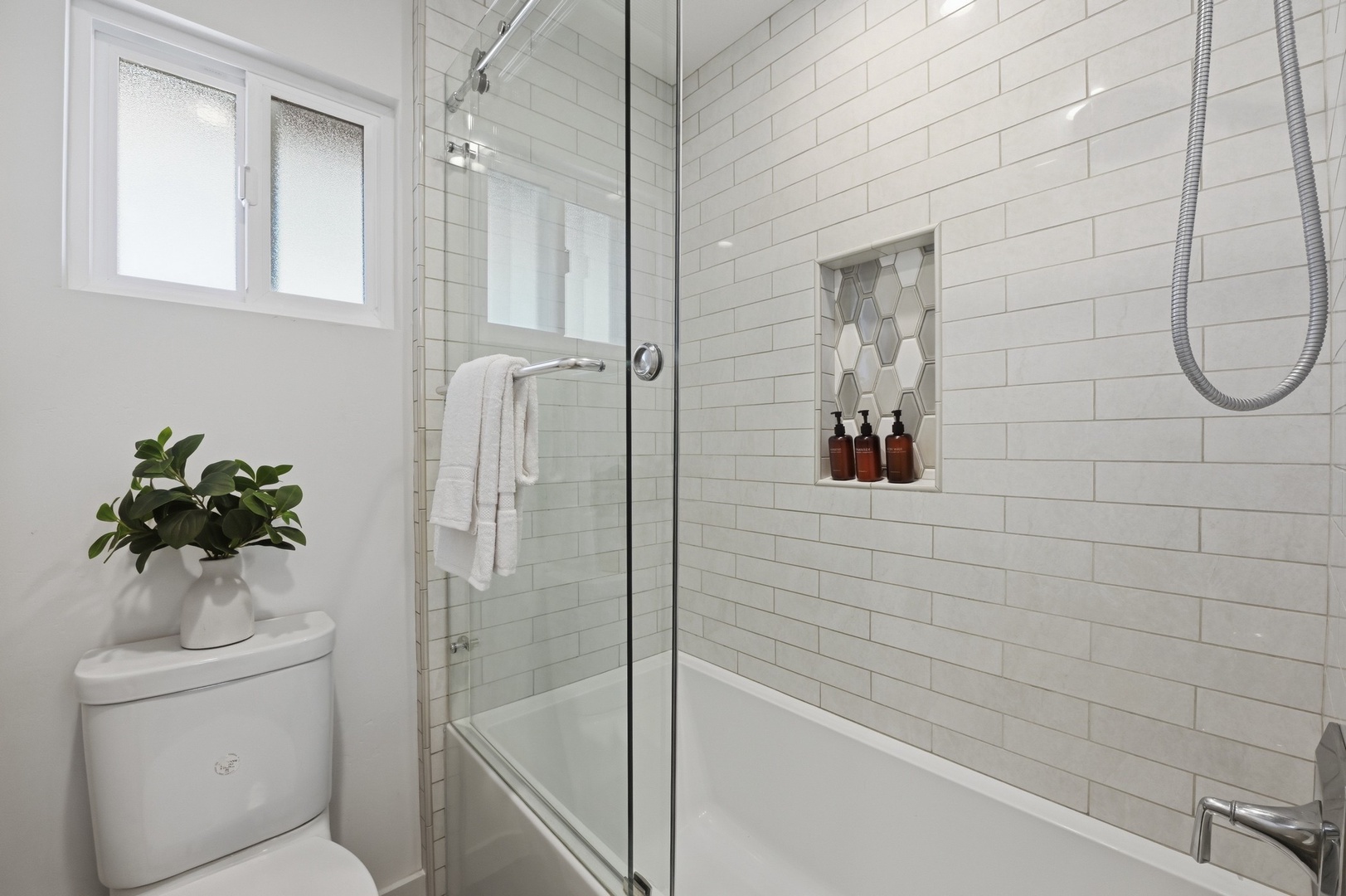 Refresh in your elegant bathroom featuring crisp subway tiles, gleaming glass shower doors, and a convenient built-in niche for your toiletries.
