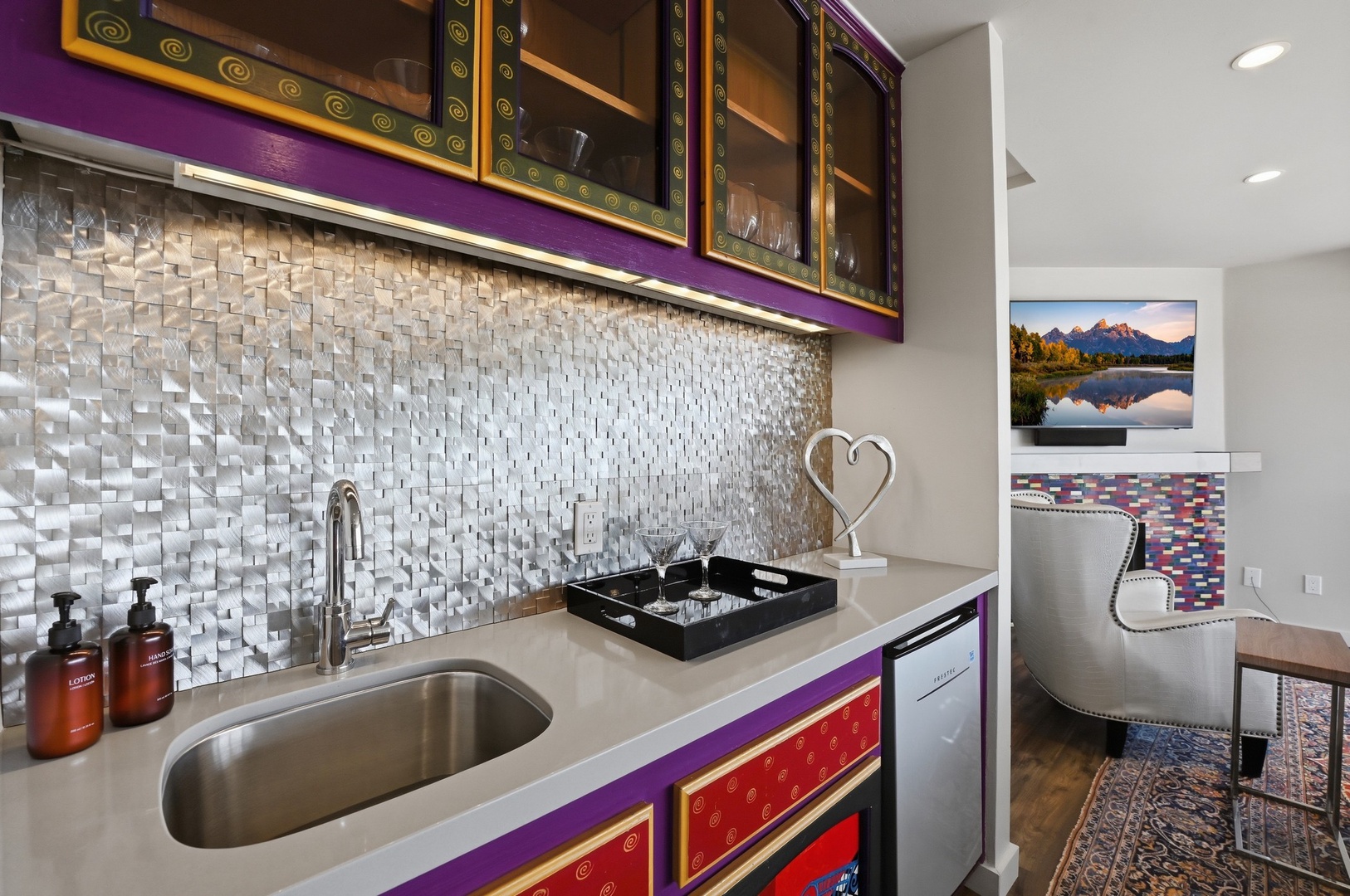 Your vibrant kitchen features colorful cabinetry, sparkling tile backsplash, and modern appliances perfect for preparing meals during your stay.