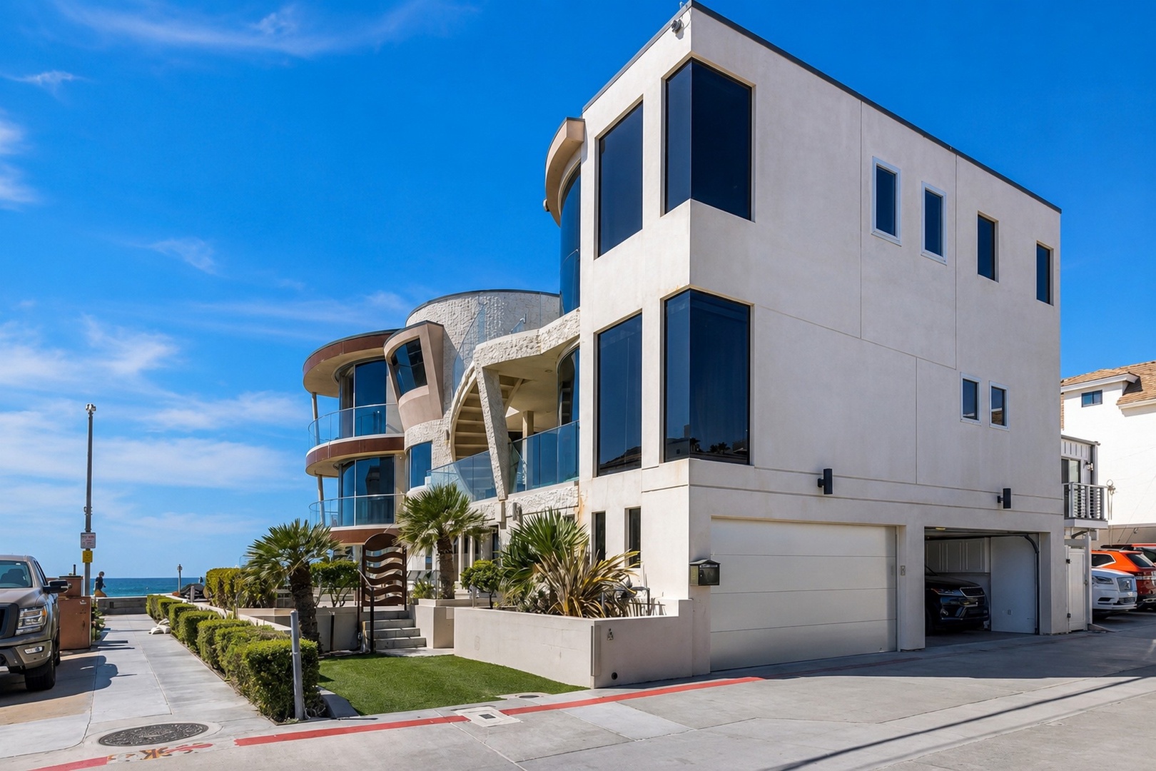 Modern beachside property featuring bold architectural lines, three-story design, and palm-tree landscaping, offering luxury and contemporary style.