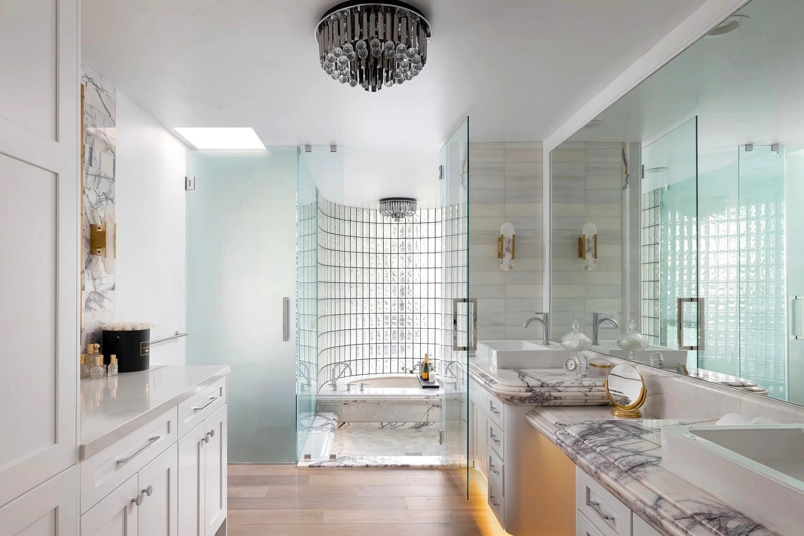 Step into your luxurious spa-like retreat with marble counters, rainfall shower, and elegant chandelier lighting.