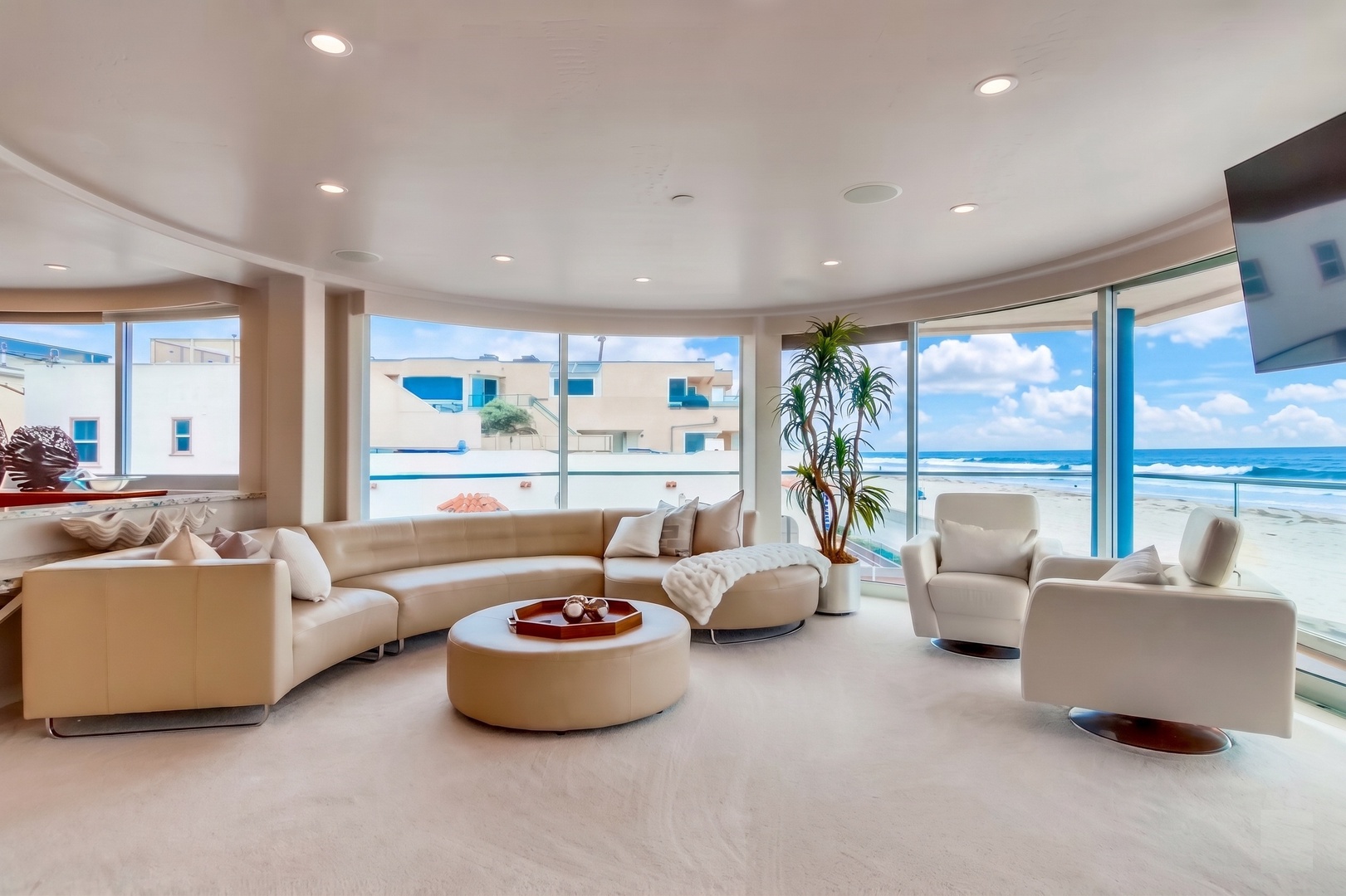 Step into your bright, modern living room where floor-to-ceiling windows frame stunning ocean views. Sink into plush seating and let the calming sea breeze wash over you.