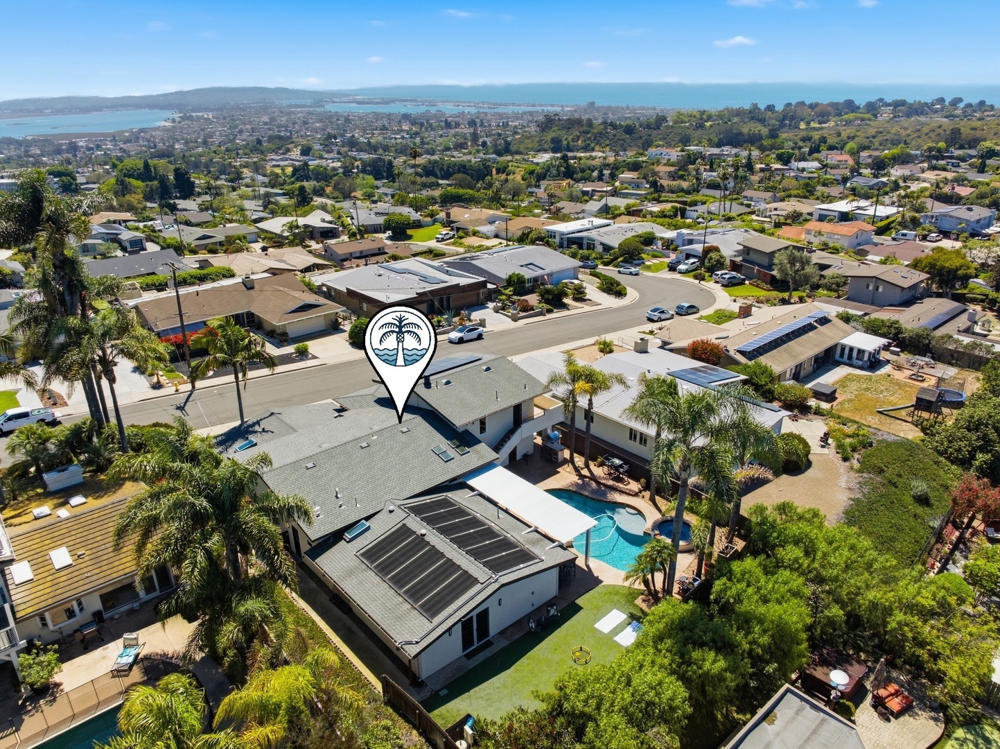 Aerial view showcases the property's prime location in a residential neighborhood with ocean views in the distance.