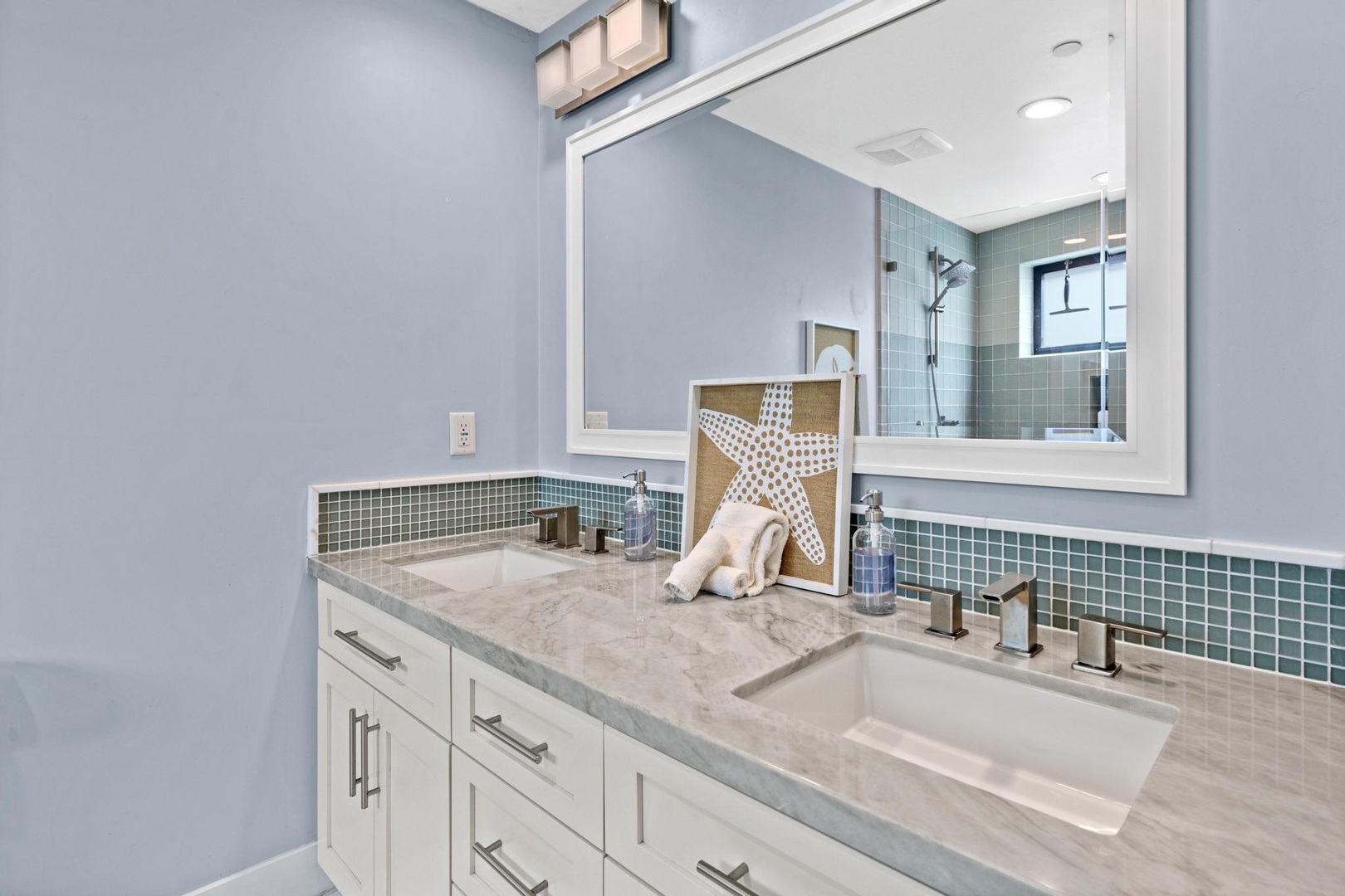 Imagine getting ready in this beautifully designed coastal-themed bathroom, with its soothing ocean-inspired tile and elegant dual vanity perfect for your morning routine.