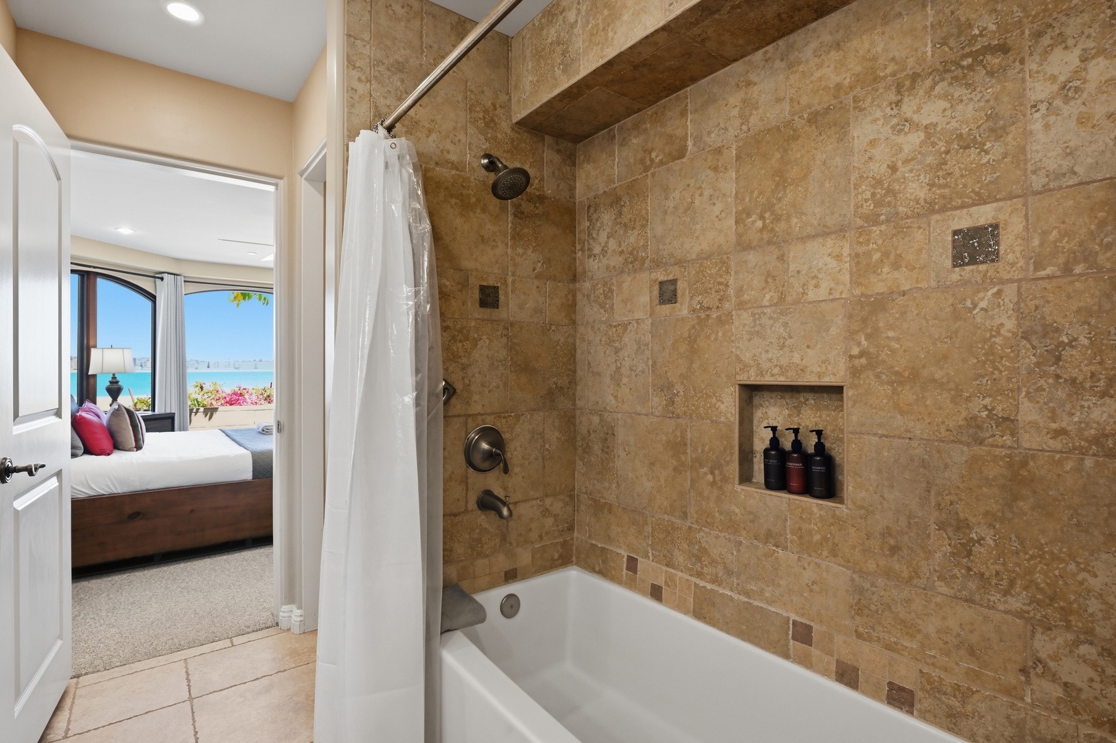 Soak in your elegant stone-tiled bathroom with stunning sea views just beyond your bedroom window.