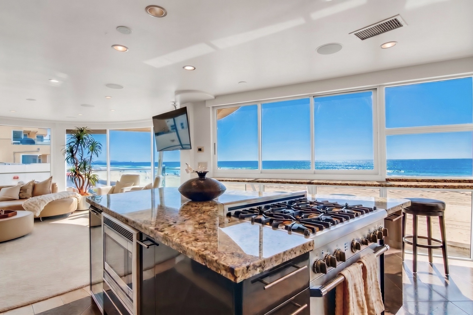 Your gourmet kitchen awaits, where preparing meals becomes pure pleasure with sweeping ocean views through floor-to-ceiling windows, a chef's gas range, and a sleek island perfect for morning coffee or sunset appetizers.