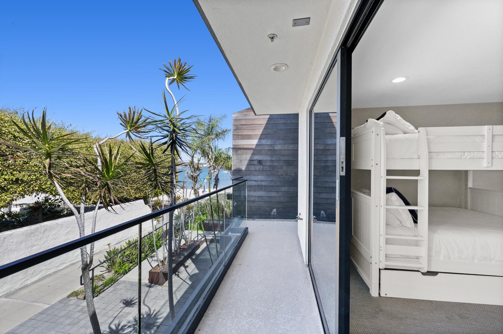 Step onto your private balcony where tropical plants frame stunning ocean glimpses. Inside, a cozy bunk bed awaits—perfect for kids or extra guests seeking seaside dreams.