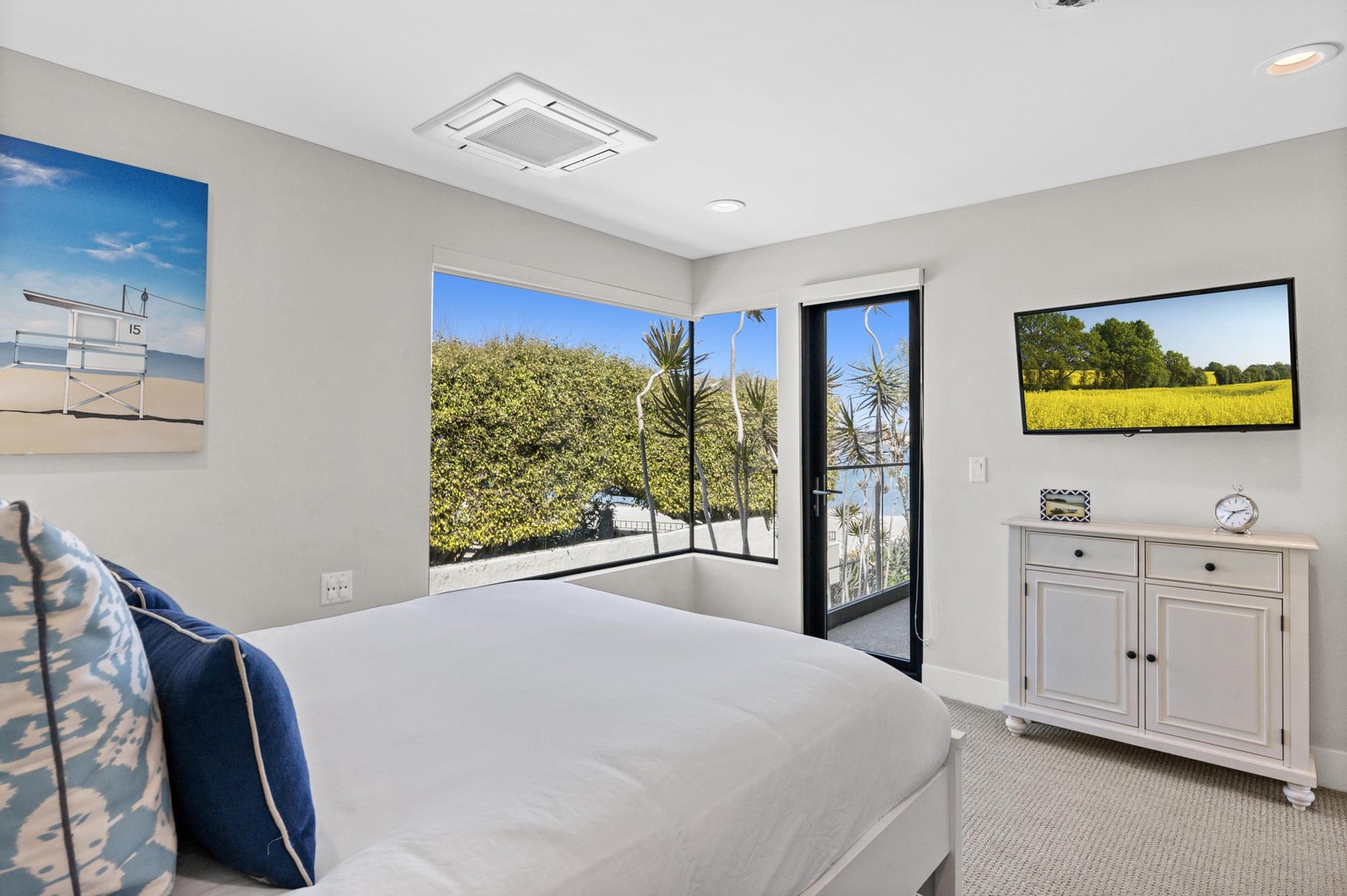 Slip into crisp linens and wake to sunshine streaming through glass doors opening to greenery. Your coastal bedroom pairs relaxation with scenic outdoor access.