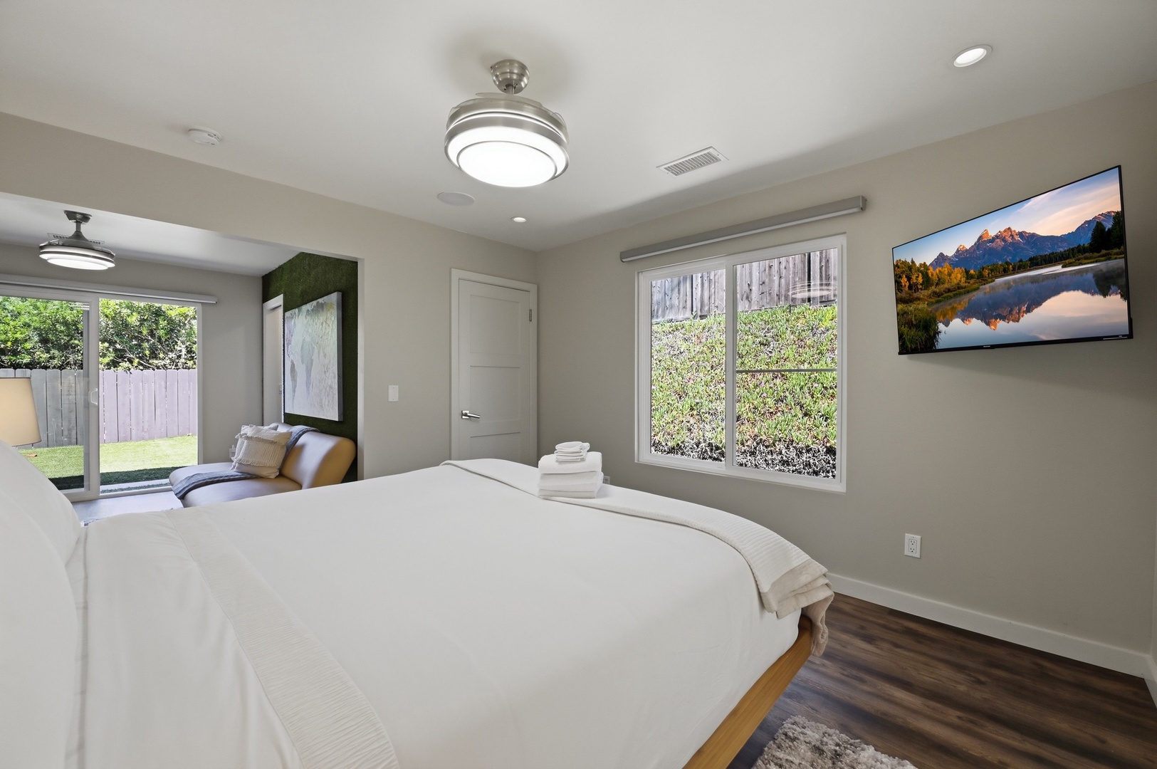 Wake up refreshed in your bright, modern bedroom with crisp linens and peaceful garden views streaming through large windows.