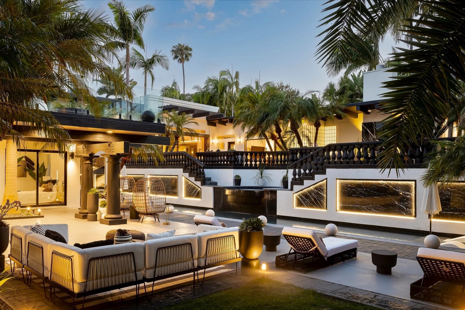 Unwind in tropical luxury on this stunning terrace, where palm trees frame your private paradise under warm evening lights.