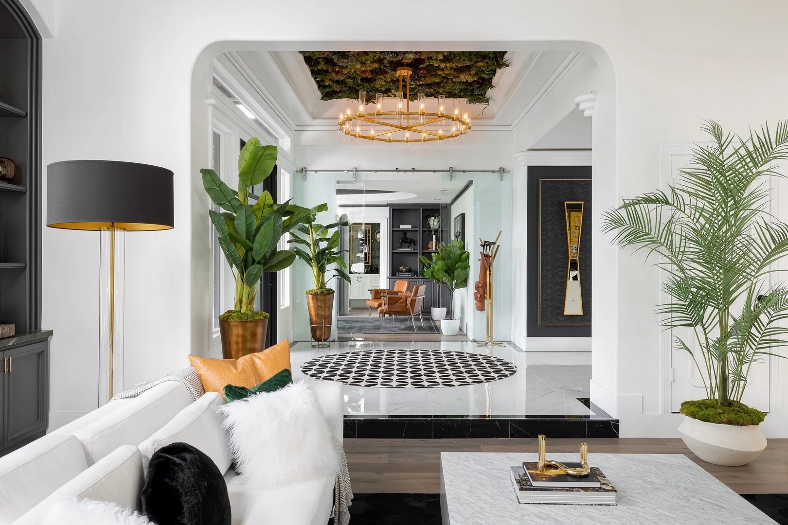 Sink into plush white sofas surrounded by lush greenery and golden accents that create your sophisticated urban sanctuary.