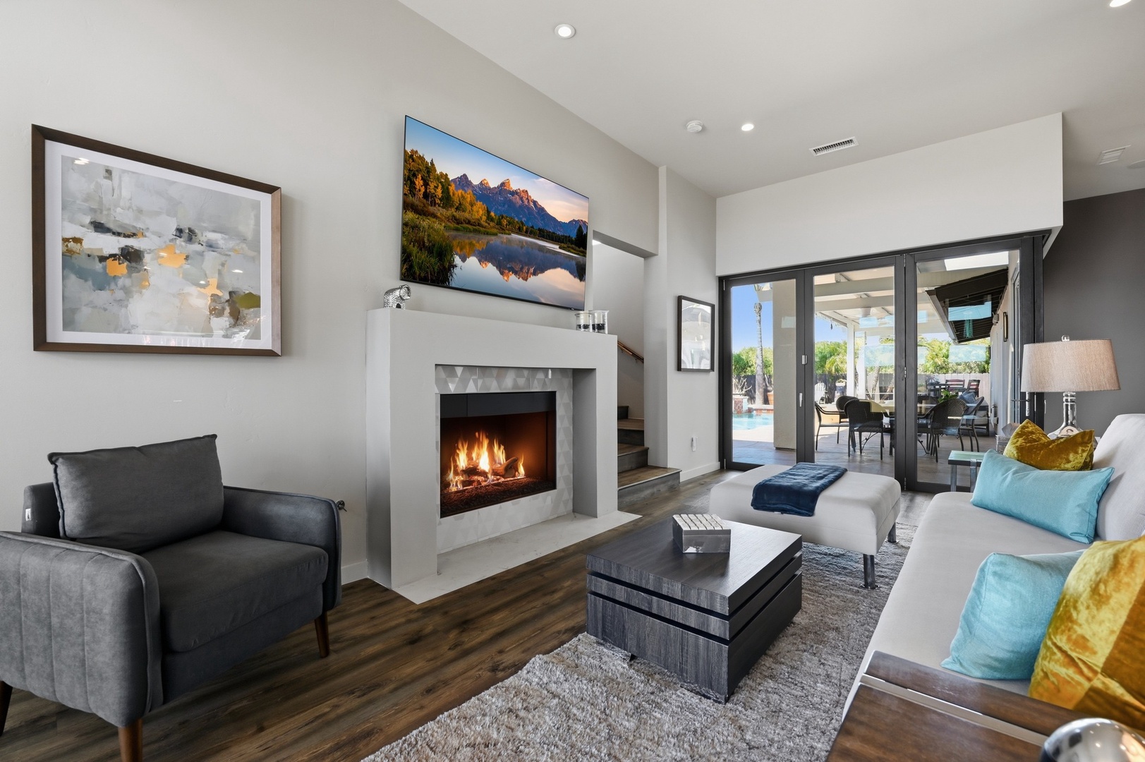 Cozy up in your stylish living room with a crackling fireplace, modern entertainment, and pool views through sliding glass doors.