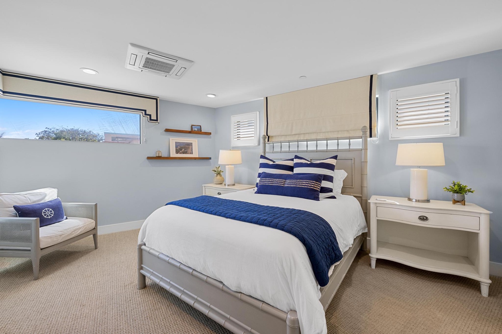 Drift off in your serene coastal-inspired bedroom, where soft blue tones, crisp white linens, and warm bedside lighting create a peaceful retreat for restful nights.