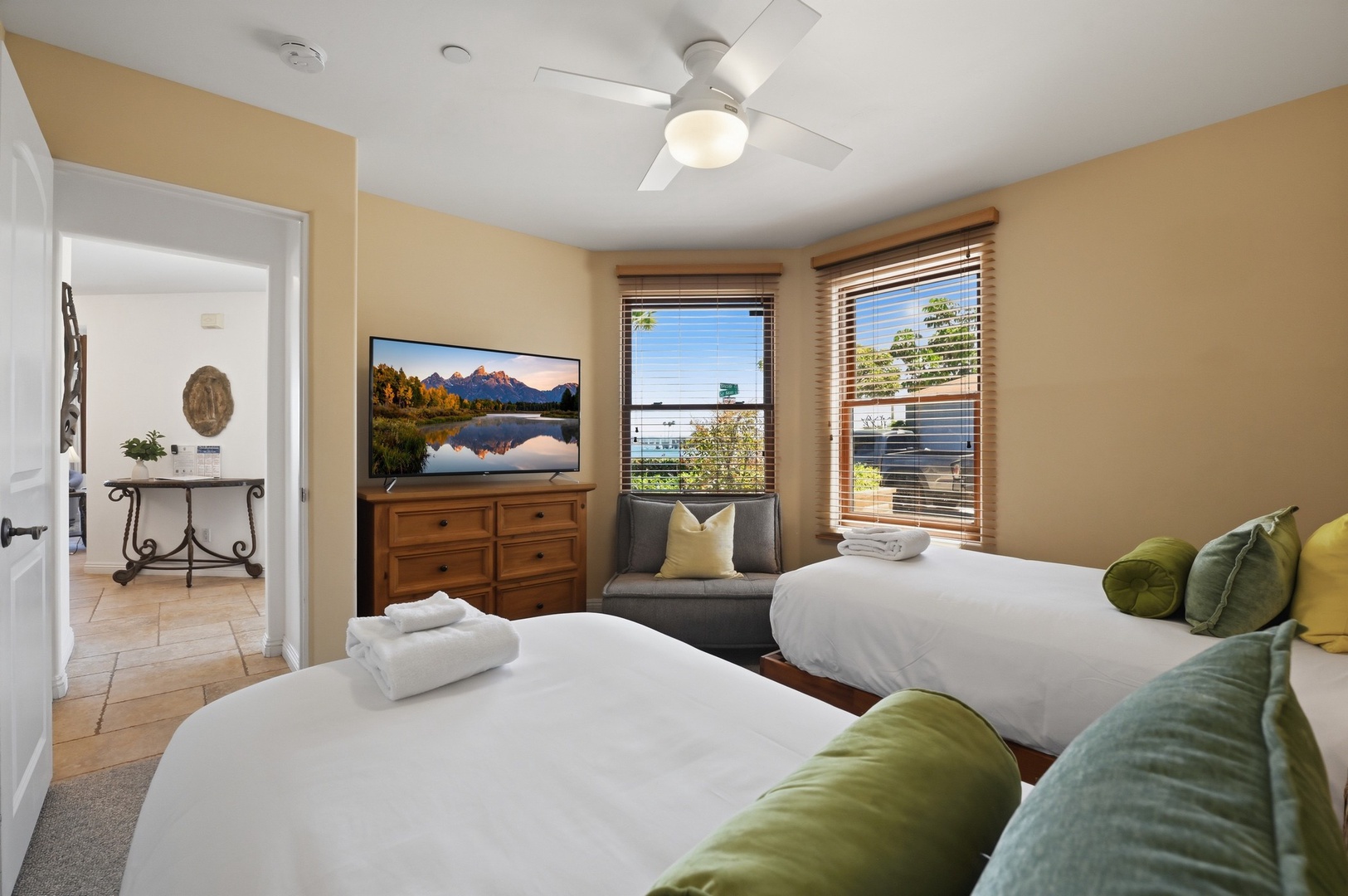 Relax in your bright bedroom with two comfy beds, ceiling fan, and large TV for cozy evenings after exploring.