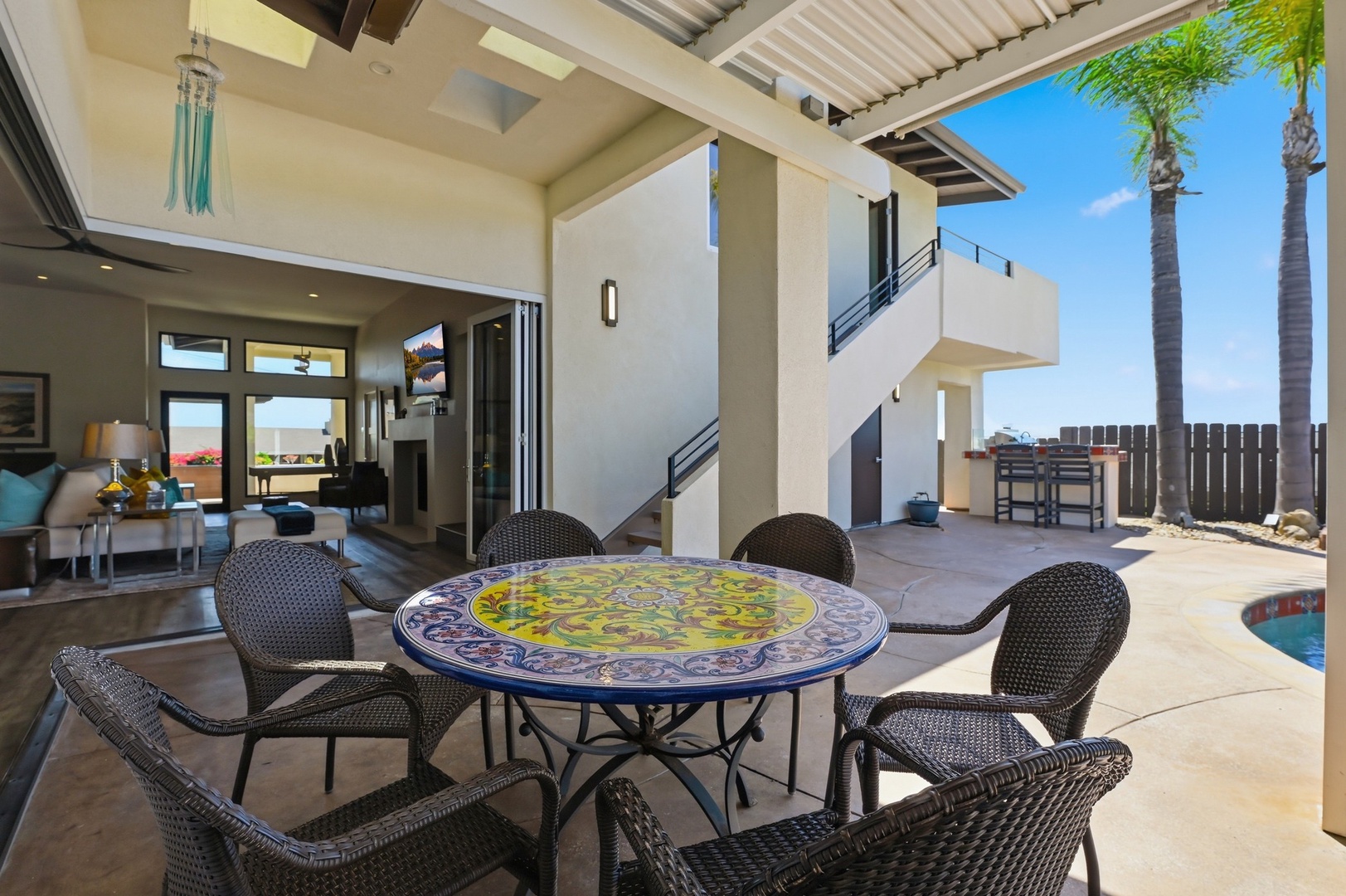 Your colorful tile-topped dining table awaits under swaying palms, perfect for morning coffee or evening meals by your private pool.