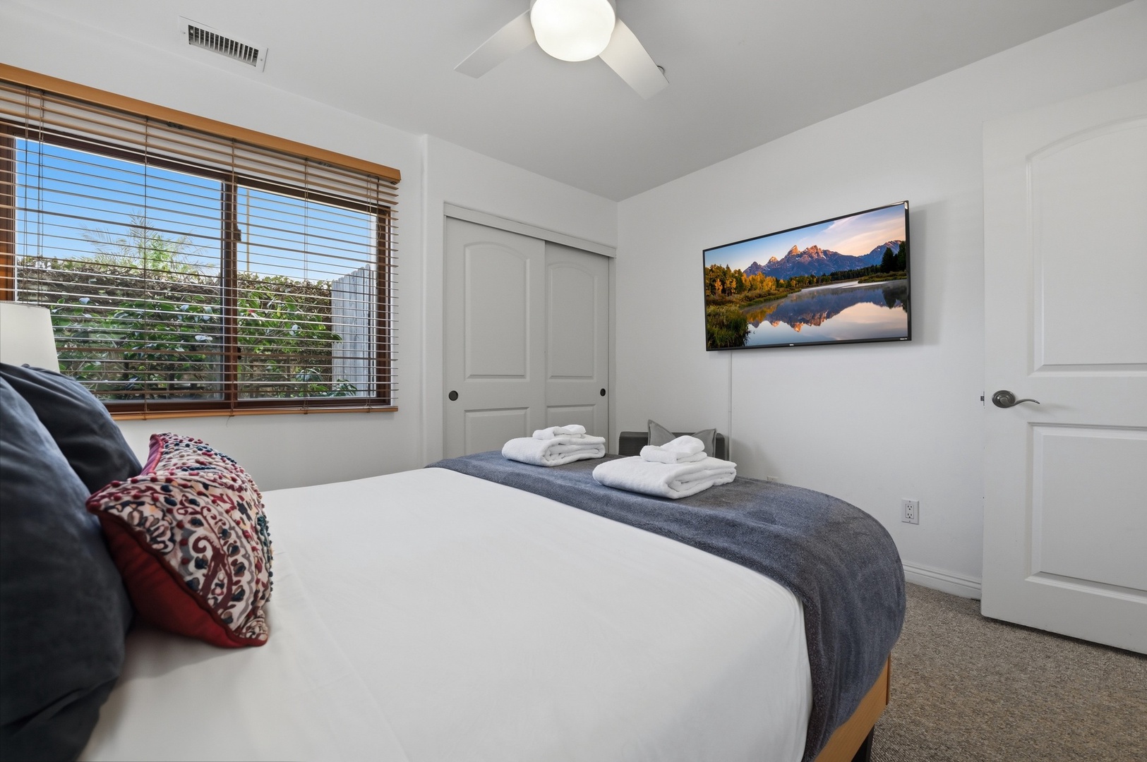 Sink into crisp white linens while enjoying your favorite shows on the wall-mounted TV in this serene bedroom retreat.