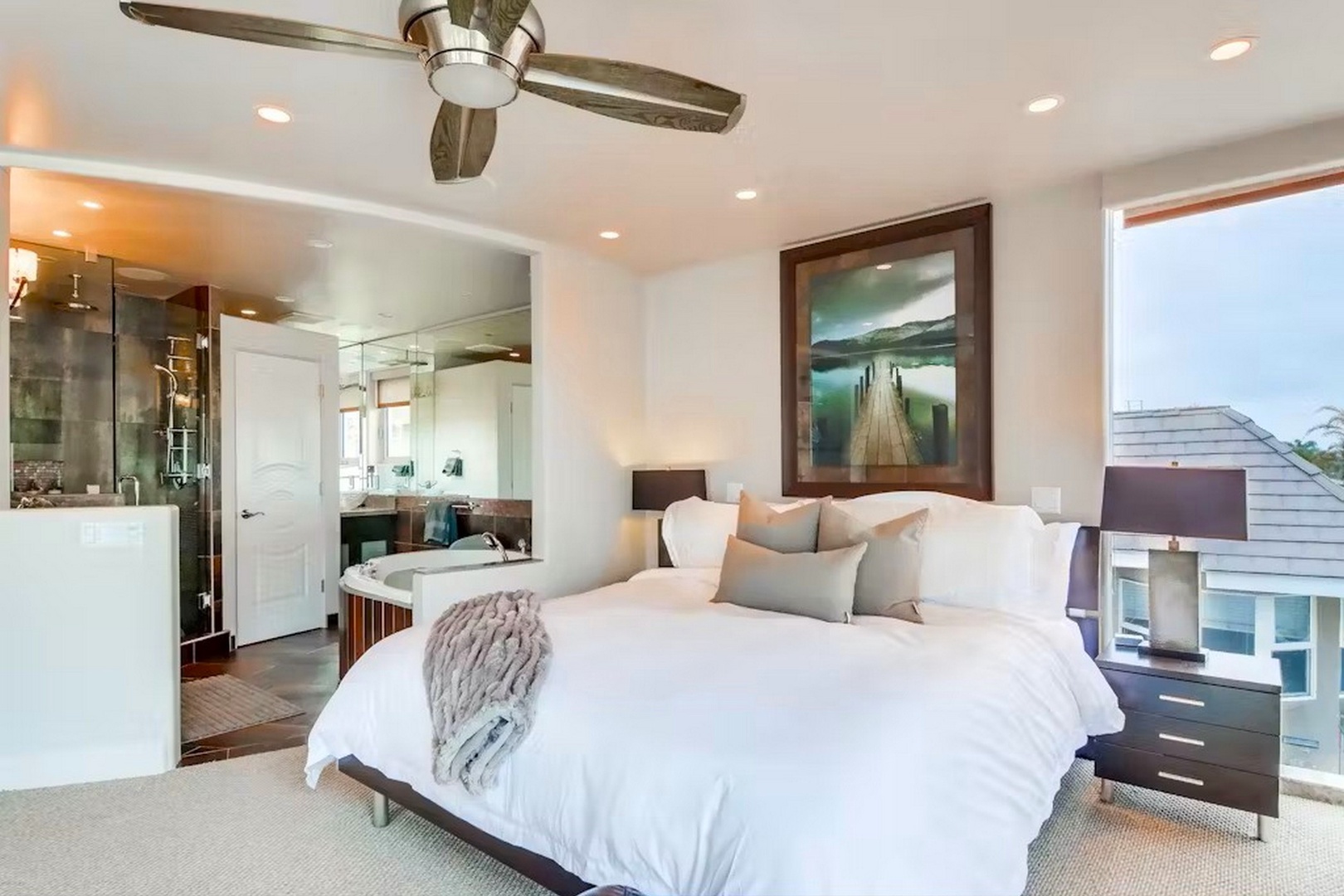 Sink into crisp white linens and let the ceiling fan cool you after a day exploring. Your en-suite spa bathroom awaits, visible through the open door.
