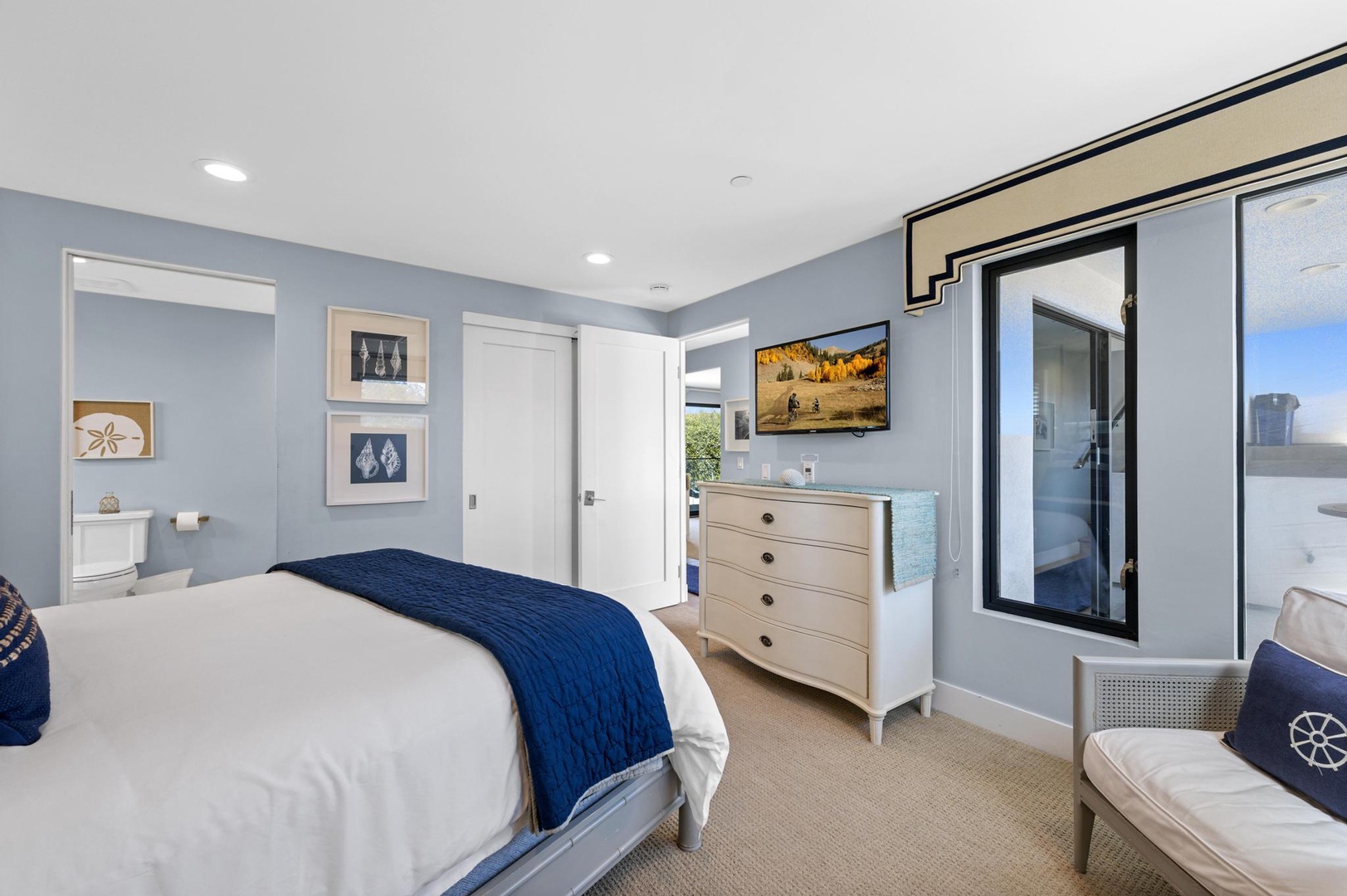 Your serene coastal retreat awaits with calming blue tones, plush bedding, and thoughtful nautical touches that frame peaceful moments by the sea.