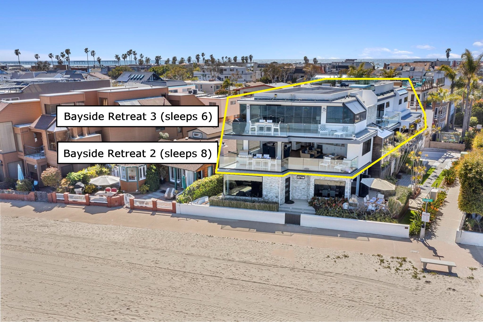 Modern beachfront property featuring two connected retreats with direct beach access, surrounded by coastal palms and neighboring homes in a sunny bayside location.