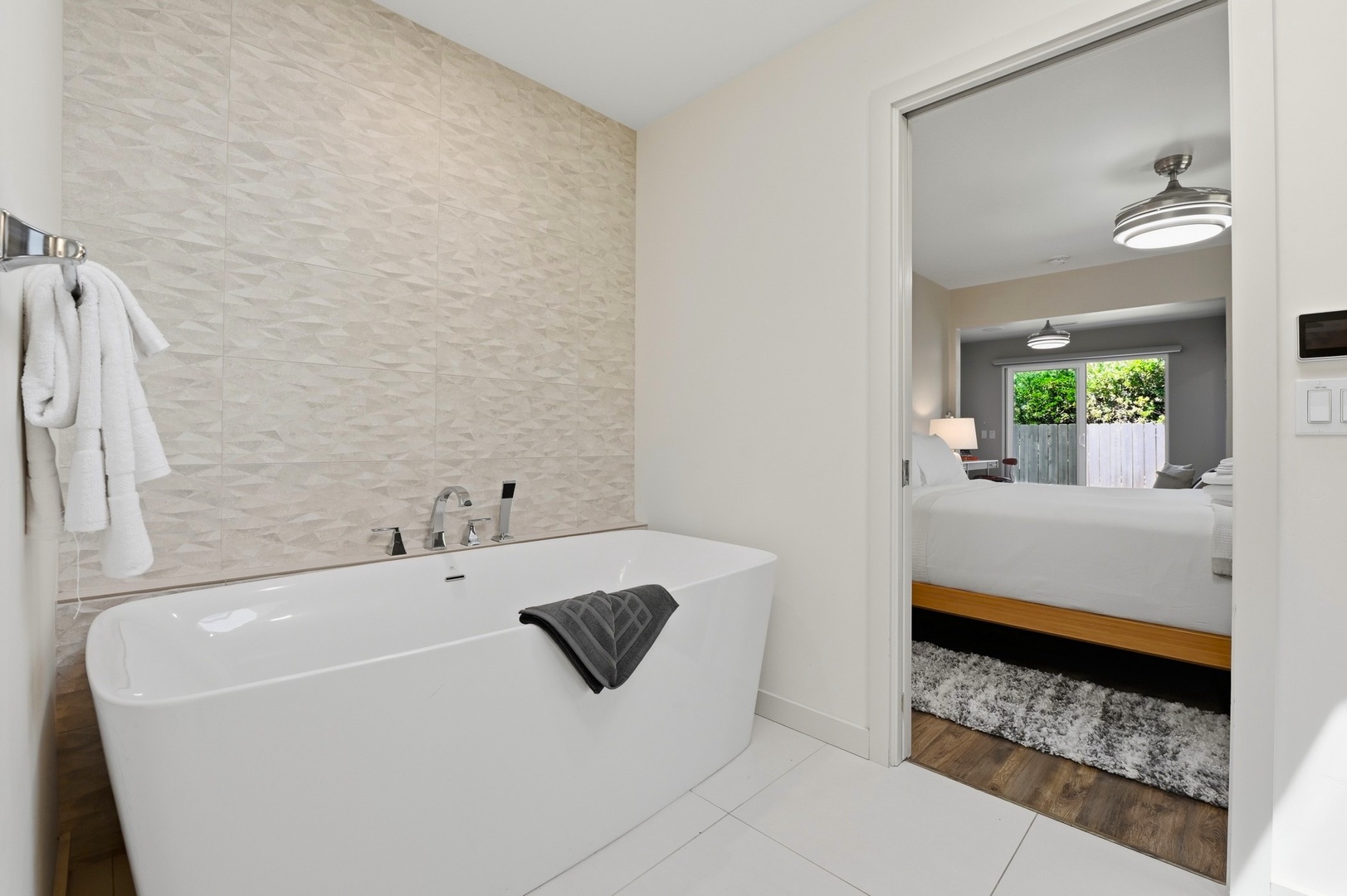 Unwind in your luxurious soaking tub with spa-like textured walls and plush robes waiting nearby.