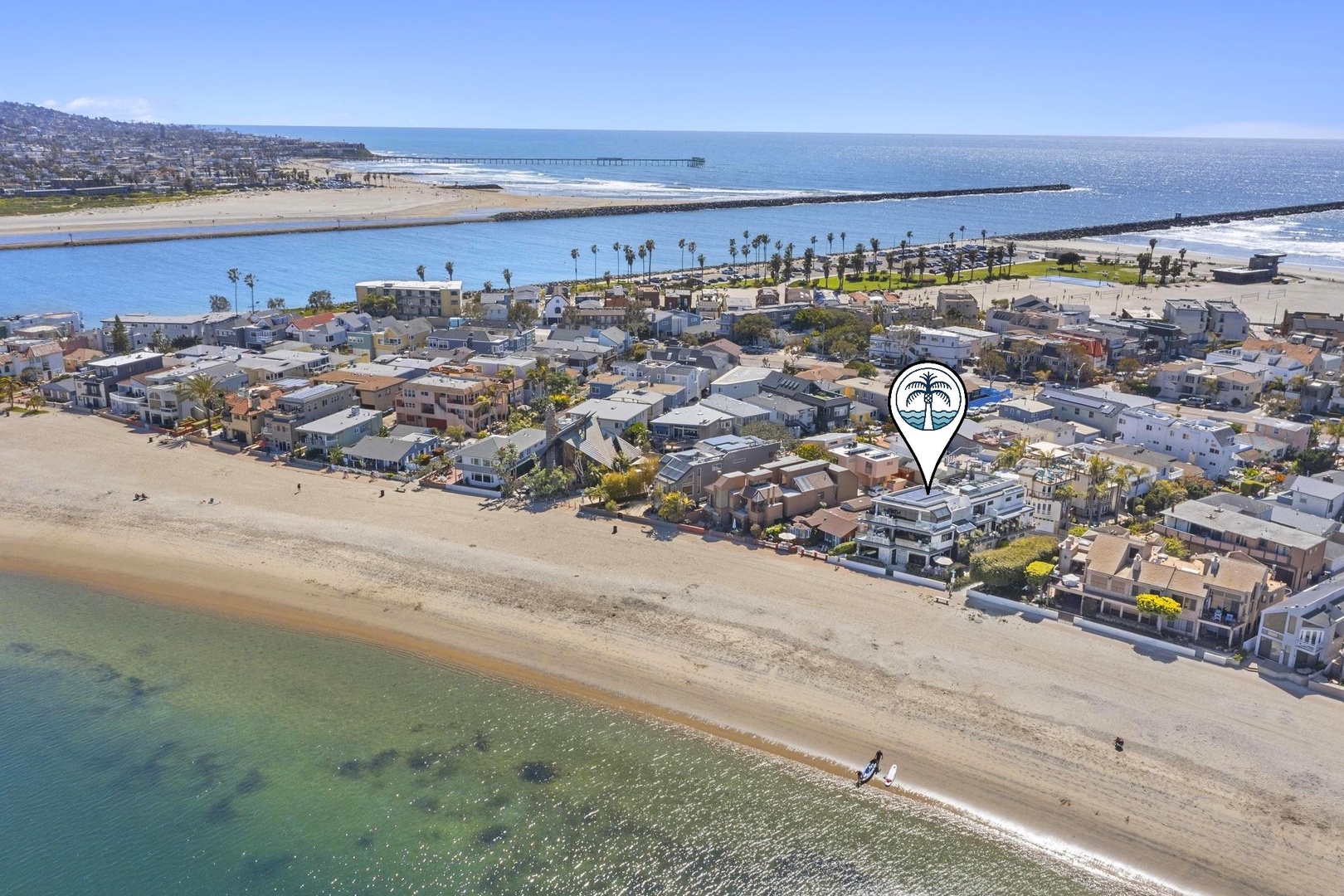 Aerial view of a beachfront community nestled between ocean shores and scenic waterways, with the property located steps from sandy beaches and coastal attractions.