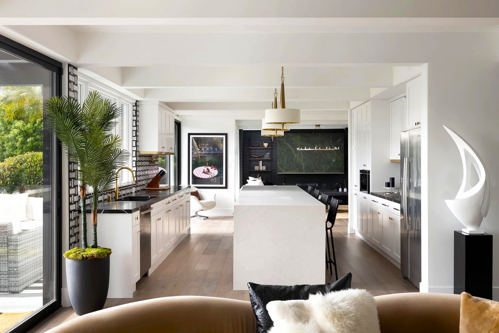 Step into this stunning open-concept kitchen where sleek white cabinetry and marble island create your culinary sanctuary. Natural light floods through floor-to-ceiling windows.