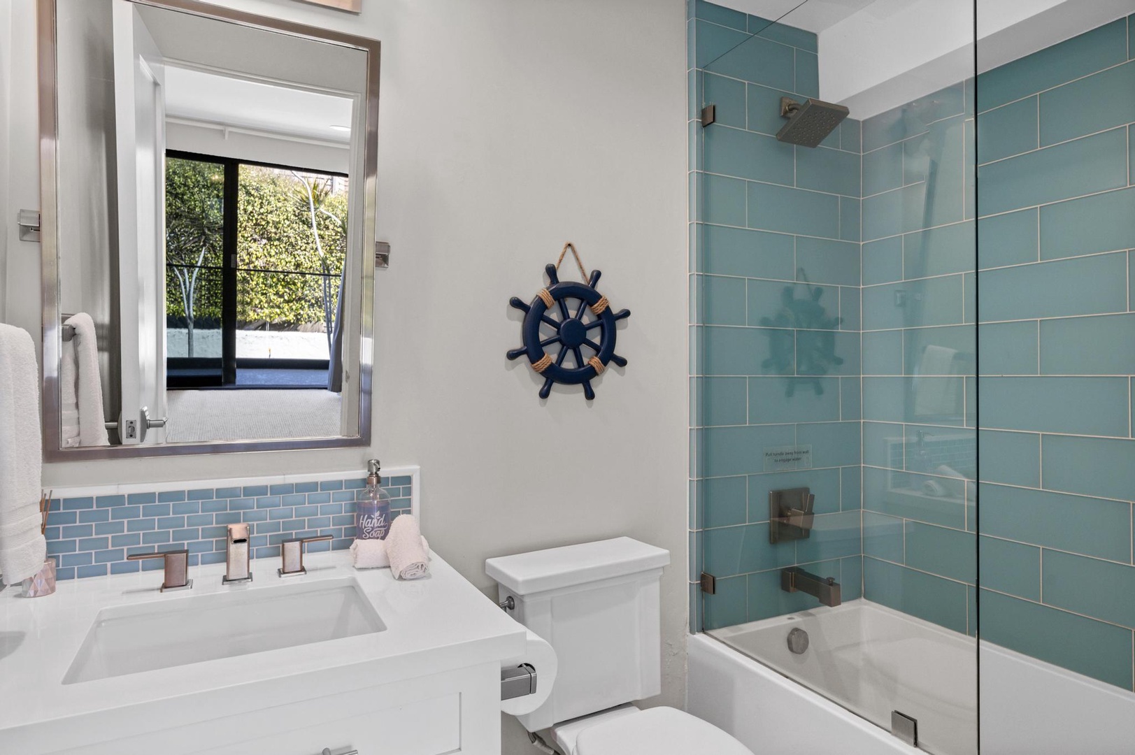 Step into your coastal-inspired bathroom with soothing blue tiles, a sleek glass-enclosed tub-shower combo, and crisp white fixtures that make every morning feel like a fresh start.