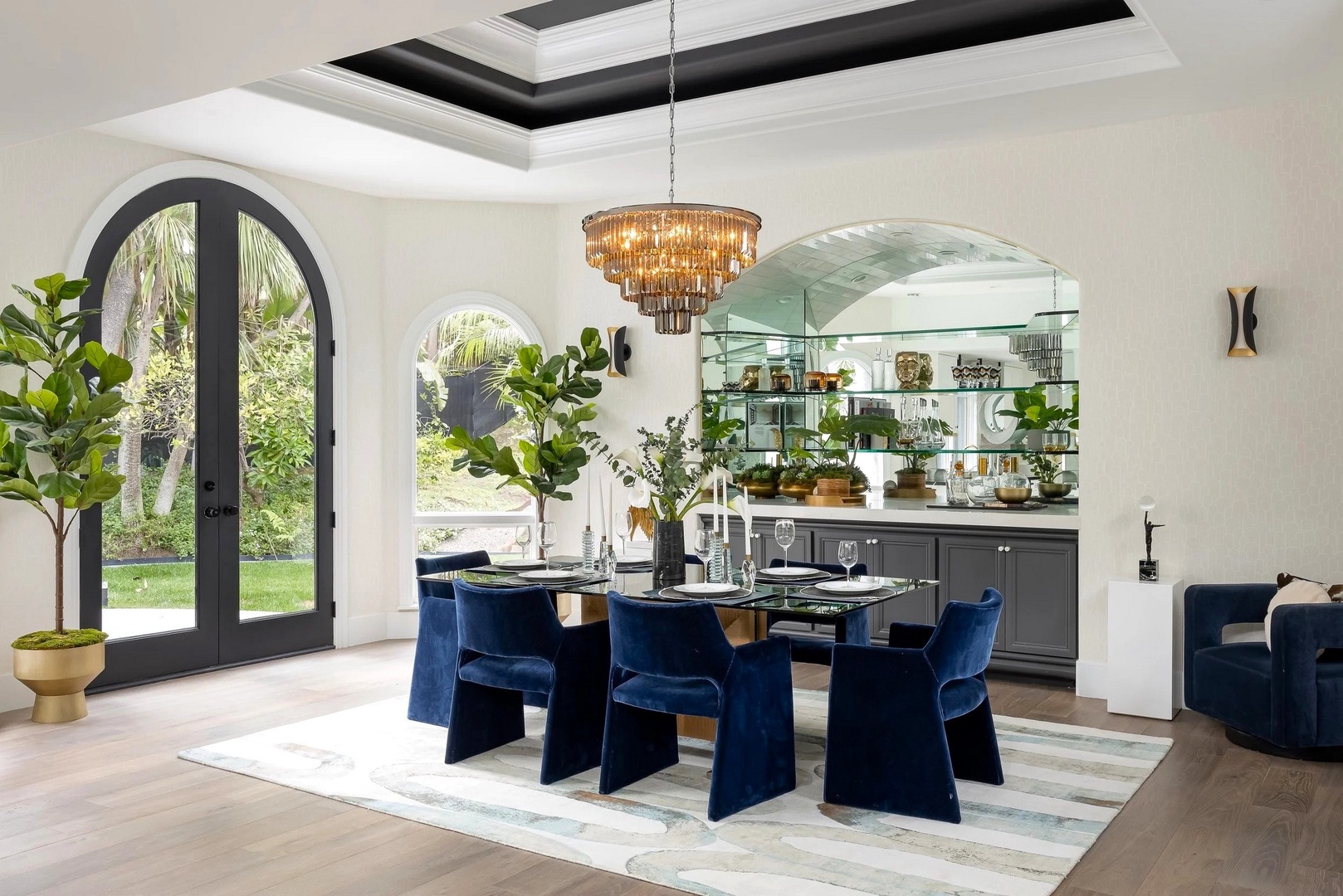 Your elegant dining space features navy velvet chairs, gleaming chandelier, and open kitchen views, perfect for memorable meals together.