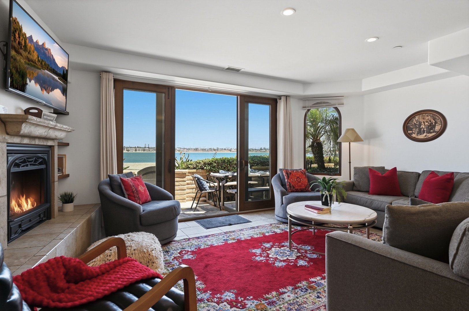 Relax in your stylish waterfront living room where cozy seating and a crackling fireplace meet stunning ocean views.