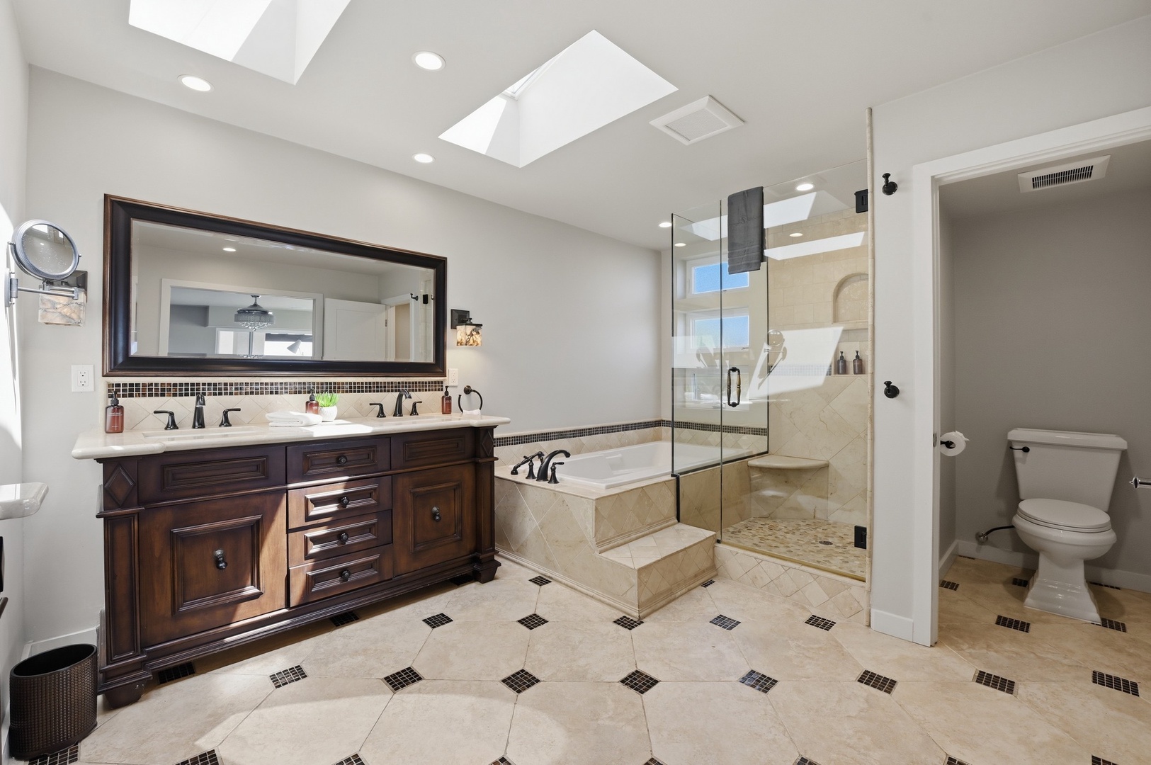 Indulge in your private spa-like bathroom with dual vanities, soaking tub, and rainfall shower beneath natural skylights.