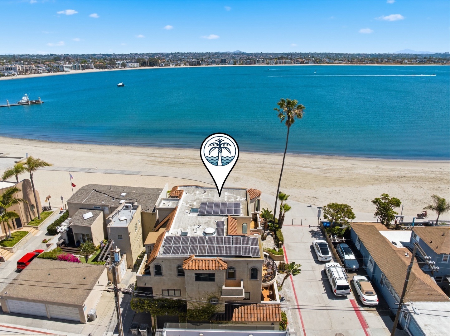 Stunning beachfront property sits directly on pristine sandy shores with crystal blue waters and tropical palms nearby.